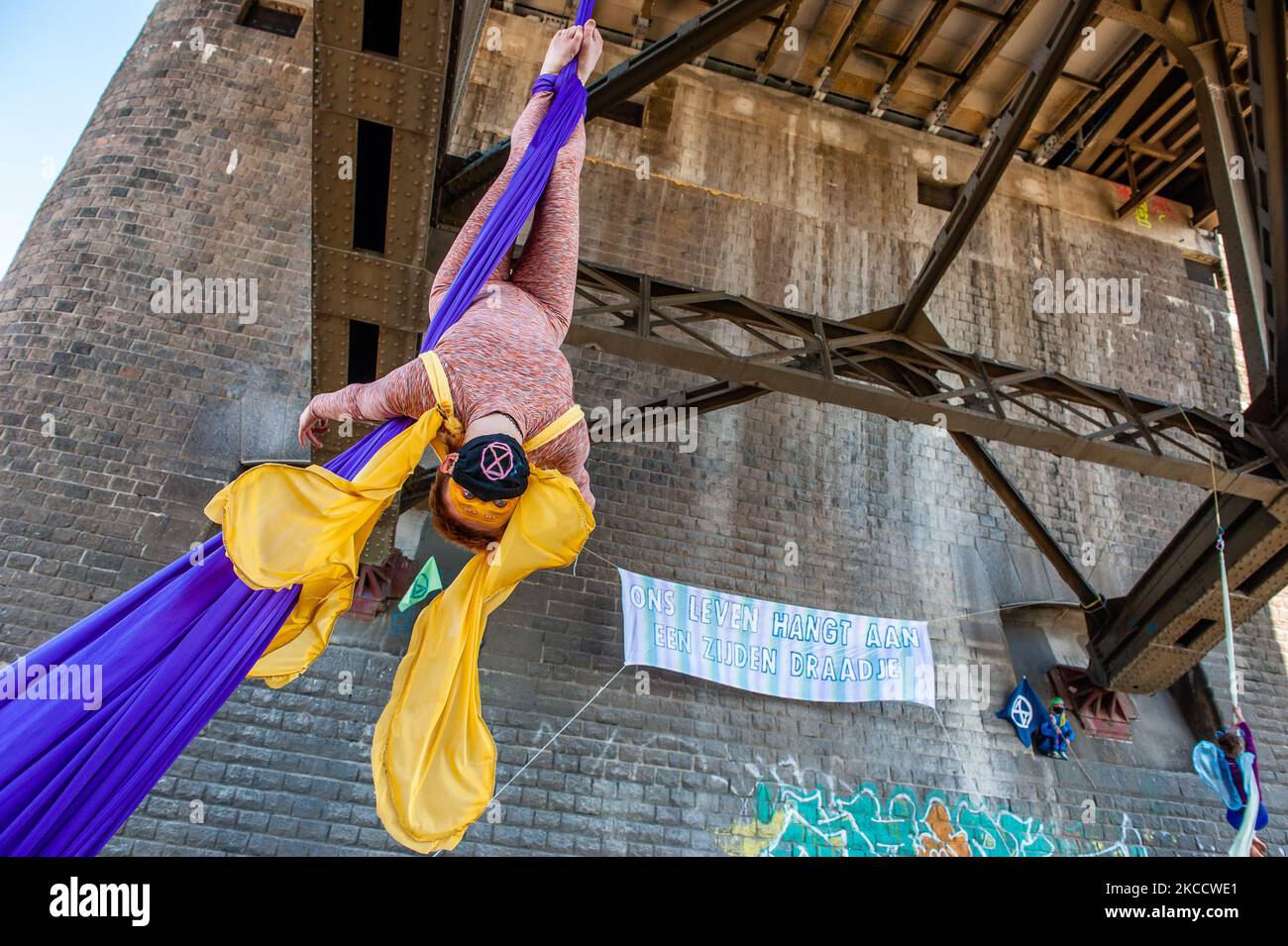 Un acrobat se produit avec de la soie aérienne tandis qu'une bannière XR est suspendue derrière elle, lors d'une action réalisée par extinction rébellion à Nimègue, sur 16 avril 2021. (Photo par Romy Arroyo Fernandez/NurPhoto) Banque D'Images