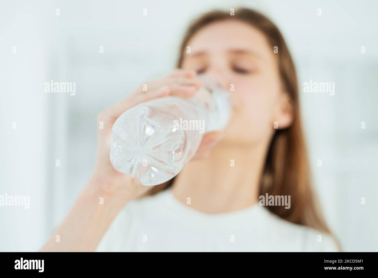 Une jeune femme adorable boit de l'eau dans une bouteille en plastique en gros plan, un mode de vie sain Banque D'Images