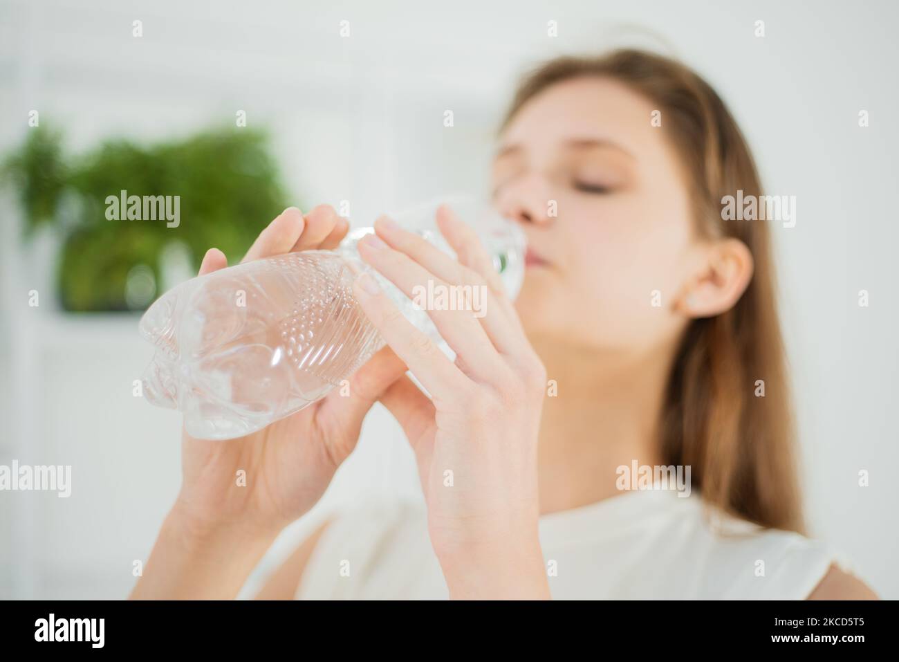 Une jeune femme adorable boit de l'eau dans une bouteille en plastique en gros plan, un mode de vie sain Banque D'Images