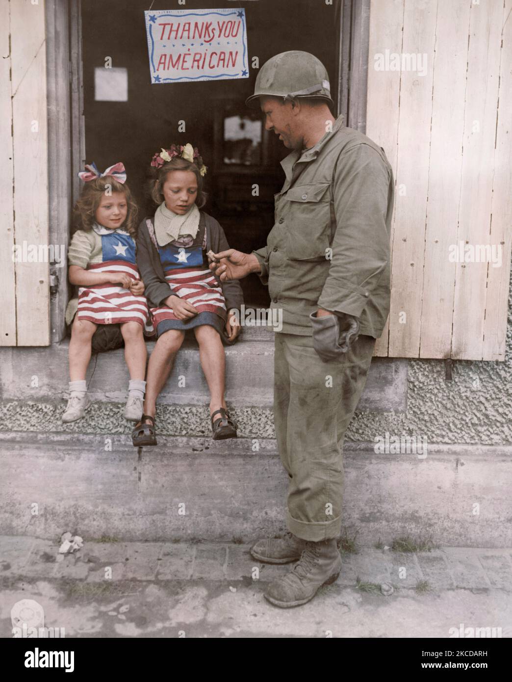 Un soldat américain traite les deux petites filles françaises avec certains G.I. candy. Banque D'Images