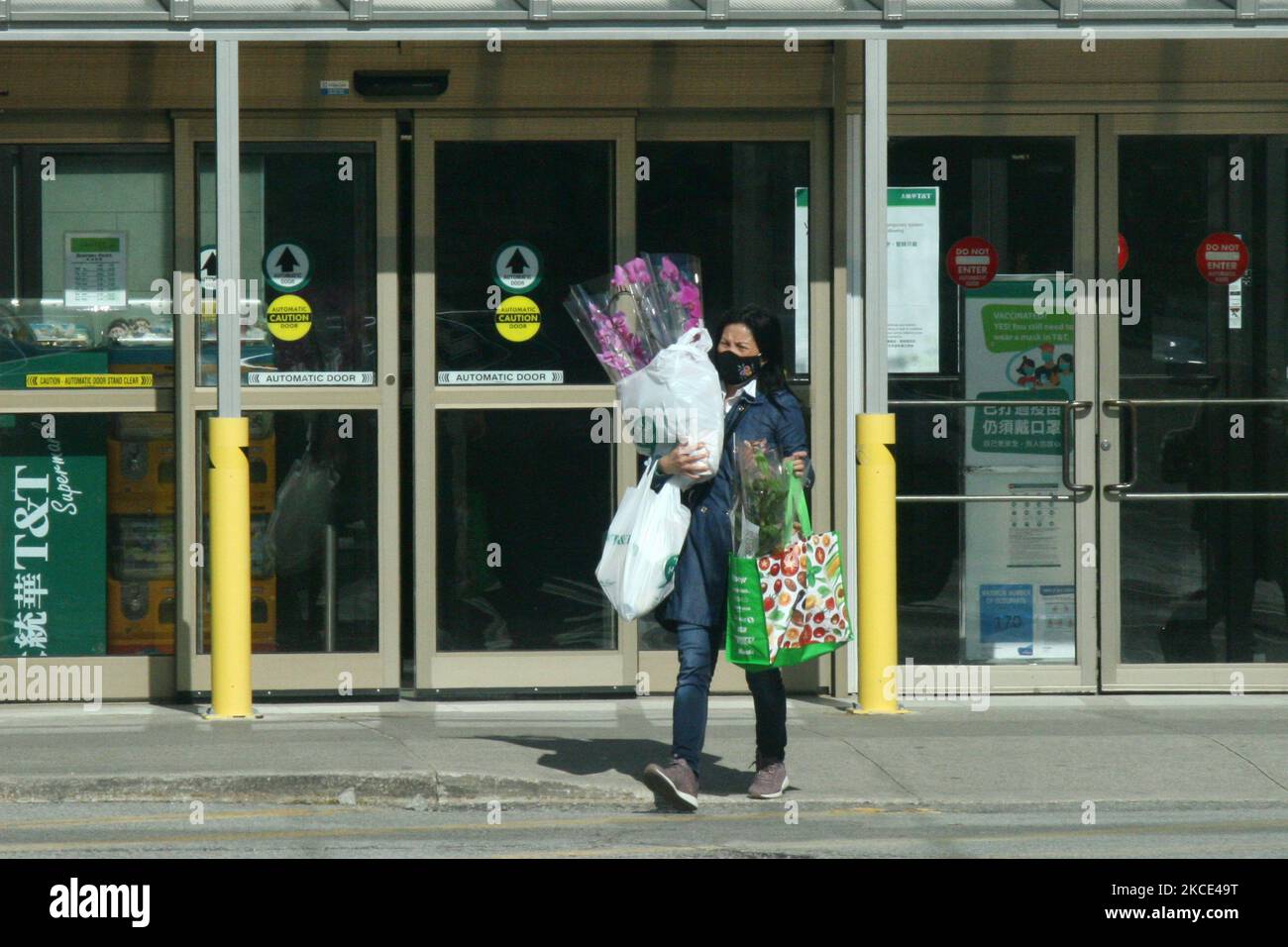 Femme portant un masque facial lors de la pandémie du nouveau coronavirus (COVID-19) alors qu'elle transportait des plantes d'orchidées qu'elle avait achetées pour la fin de semaine de la fête des mères à Toronto, Ontario, Canada, sur 06 mai 2021. L'Ontario a fait l'objet d'une autre ordonnance de séjour à la maison dans le cadre de l'affaire COVID-19 en pleine flambée. Le décret ordonne également la fermeture de tous les points de vente au détail non essentiels pour les achats en personne et sera accompagné de la troisième déclaration d'état d'urgence de l'Ontario depuis le début de la pandémie. (Photo de Creative Touch Imaging Ltd./NurPhoto) Banque D'Images