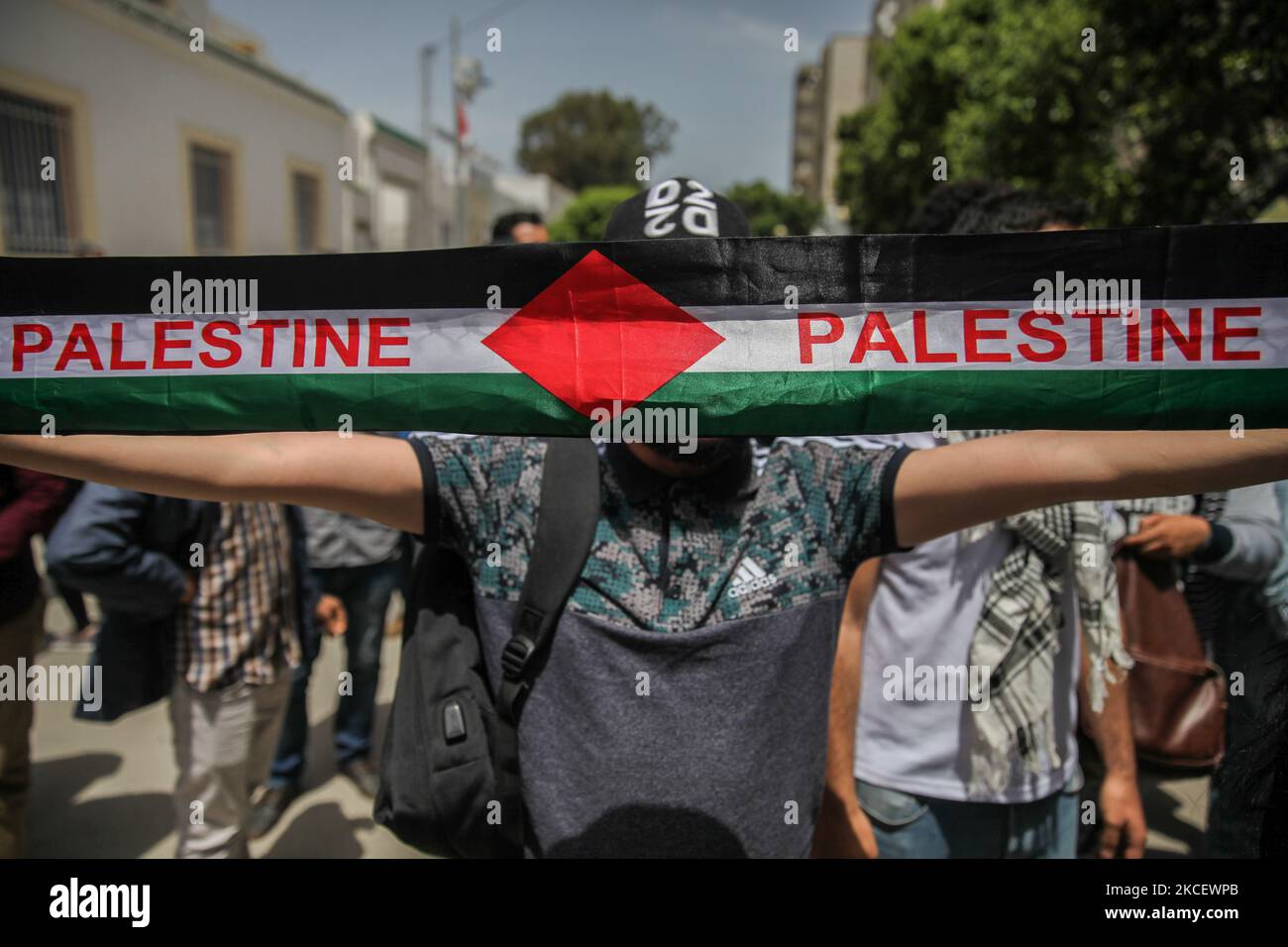 Un manifestant lève un foulard palestinien avec le drapeau palestinien lors d'une manifestation devant le bâtiment du Parlement tunisien dans la ville de Bardo Tunis, en Tunisie, sur 18 mai 2021, pour appeler à l'adoption d'une loi par le Parlement, Cela criminalise toutes les formes de normalisation des relations avec Israël. Les manifestants ont également protesté contre les frappes aériennes israéliennes dans la bande de Gaza ainsi que contre les violations israéliennes dans les territoires occupés en Palestine, en particulier dans le quartier palestinien Sheikh Jarrah à Jérusalem-est. La manifestation intervient après plus d'une semaine de violences Banque D'Images