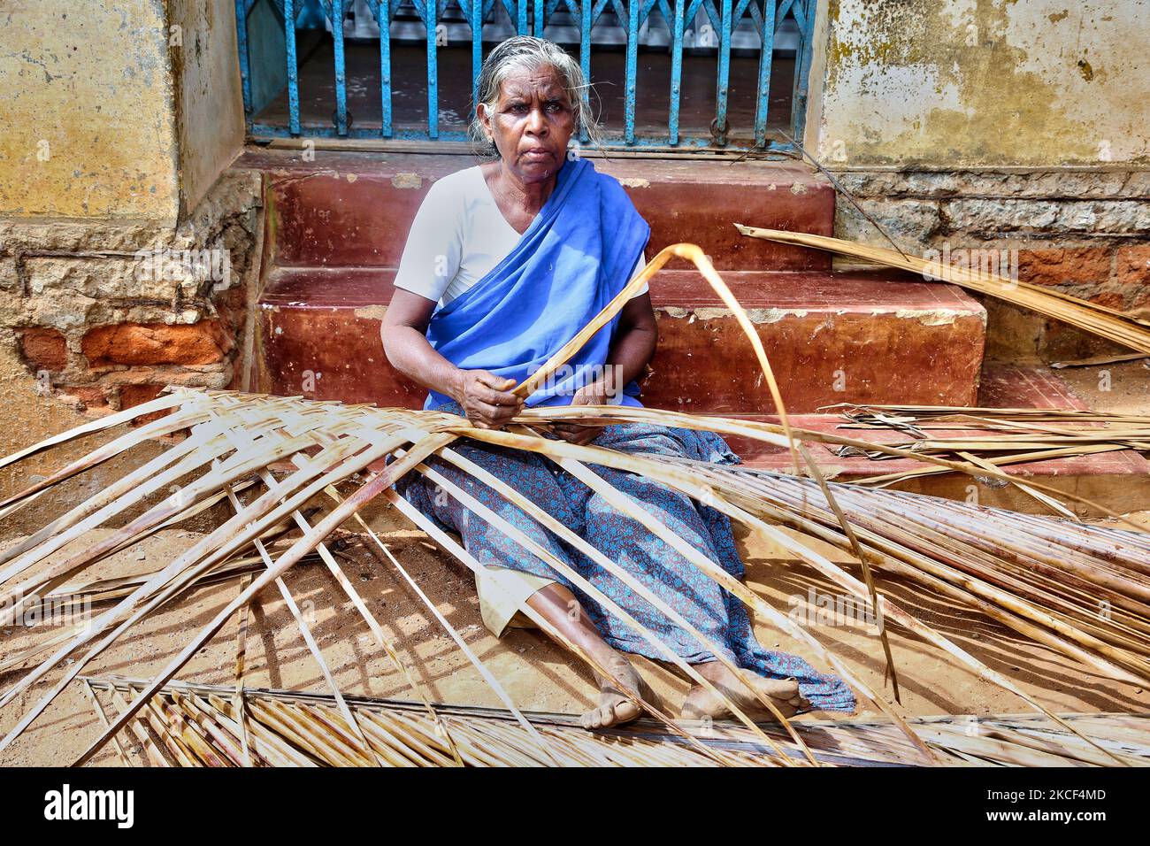 Une femme tamoule âgée serpente des murs pour sa maison rurale à partir de feuilles de palmier dans le village de Sokkankudiaruppu à Tamil Nadu, en Inde. La plupart des maisons sont construites de boue et de feuilles de palmier avec des poutres en bois pour le soutien. (Photo de Creative Touch Imaging Ltd./NurPhoto) Banque D'Images