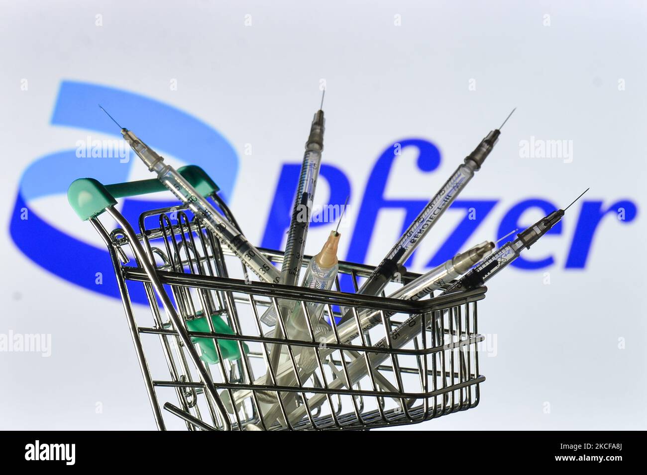 Les seringues médicales dans le mini chariot d'achat sont visibles devant le logo Pfizer affiché à l'écran. Le vendredi 28 mai 2021, à Dublin, Irlande. (Photo par Artur Widak/NurPhoto) Banque D'Images