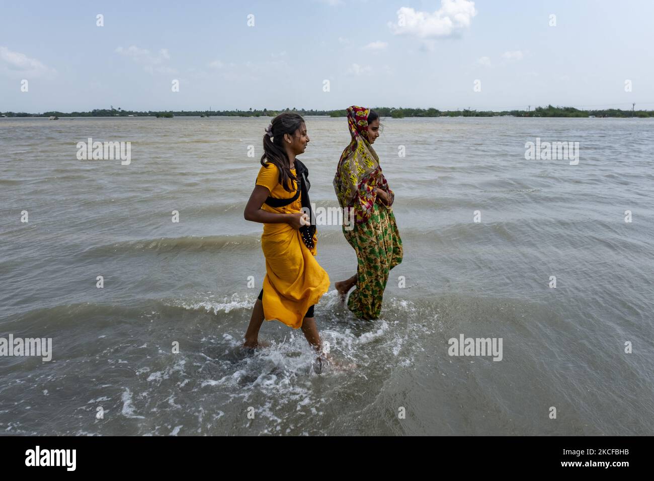 Deux jeunes filles de village traversent la route qui est pleine d'eau car les berges de la rivière se sont cassées et plusieurs villages ont été inondés. Sur 28 mai 2021 dans le sud 24 Parganas, Bengale-Occidental, Inde. Les habitants du Bengale occidental sont lourdement touchés par la rupture des berges de la rivière et l'inondation de plusieurs villages en raison de la marée haute et de fortes pluies dues au super cyclone Yaas. (Photo de Dipayan Bose/NurPhoto) Banque D'Images