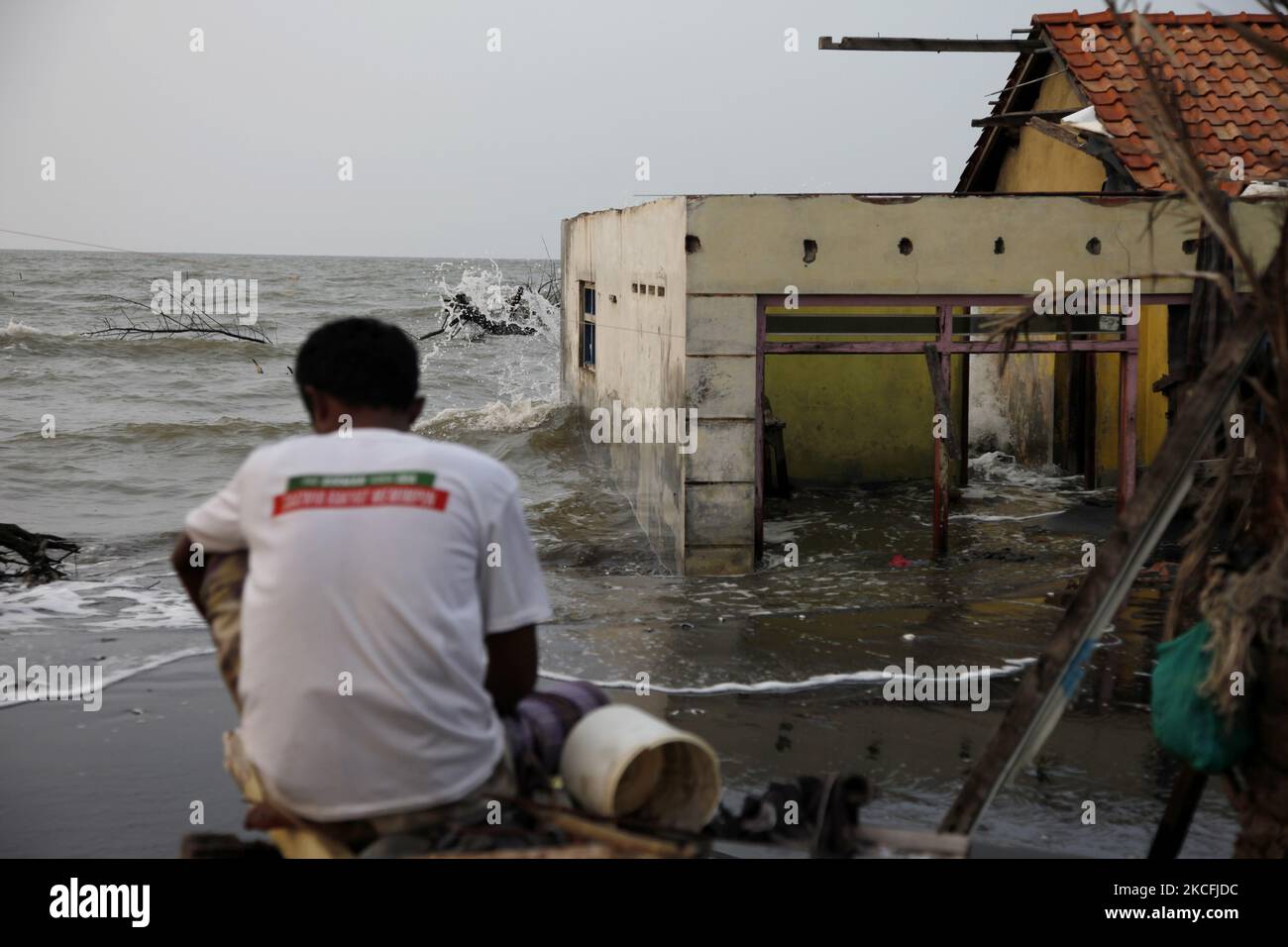 M. Rasali, assis devant sa maison détruite et noyée par l'abrasion des vagues de mer dans la côte nord de la ville de Pekalonga, au centre de Java, sur 3 juin 2021. Sur la base des données de l'Agence géologique du Ministère indonésien de l'énergie et des ressources minérales, la ville de Pekalonga connaît une affaissement des terres de 6 centimètres par an, causée par l'utilisation massive des eaux souterraines par les housolds, l'agriculture, l'industrie et le changement climatique mondial, ce qui, si ce n'est immédiatement atténué, que la ville devrait couler en 2036. (Photo par Aditya Irawan/NurPhoto) Banque D'Images