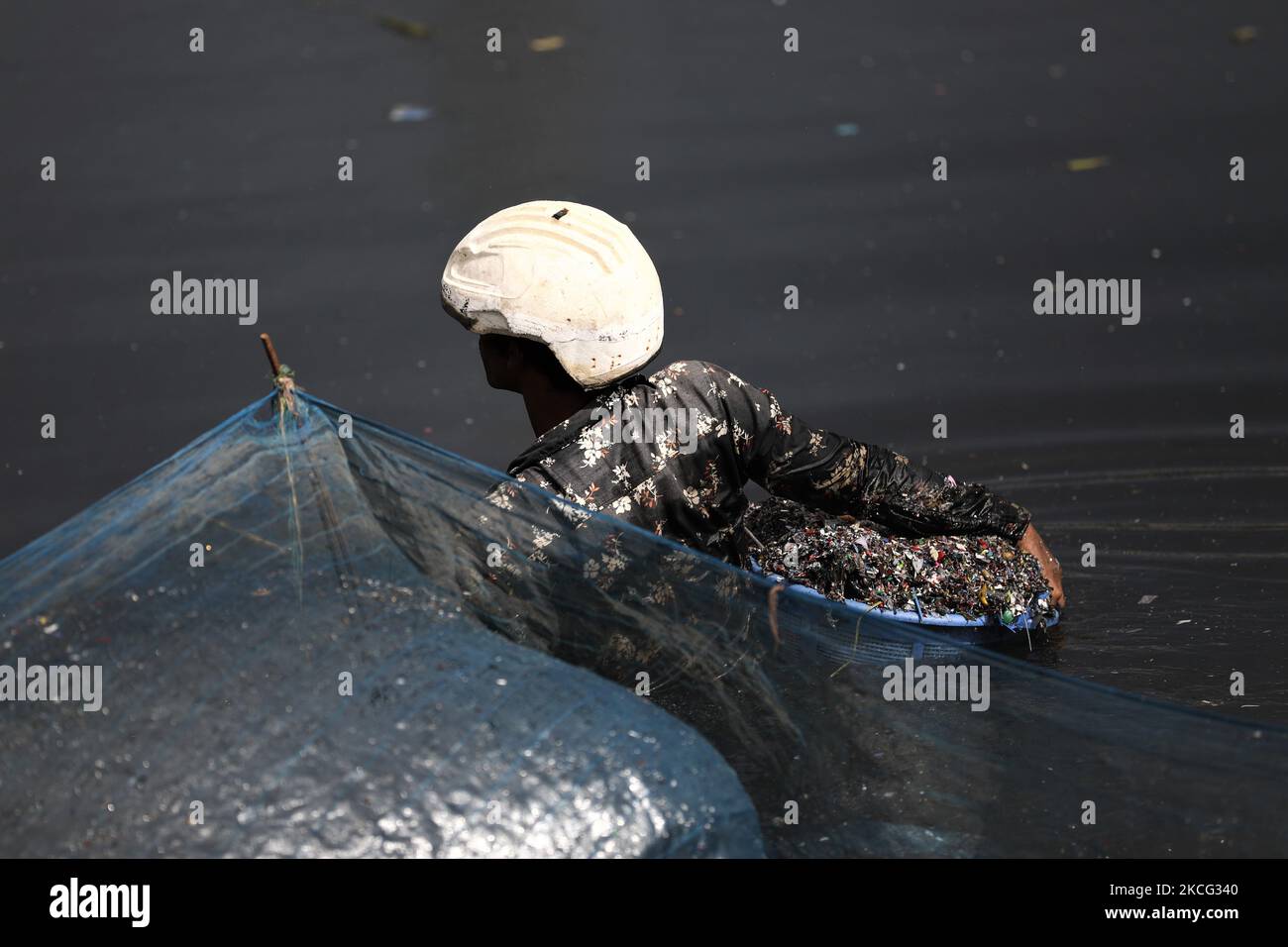 Un travailleur nettoie et collecte les pièces des bouteilles en plastique qui seront recyclées plus tard dans le fleuve Buriganga à Dhaka, au Bangladesh, sur 14 juin 2021. Le fleuve Buriganga, qui coule par la ville de Dhaka, aujourd'hui l'un des fleuves les plus pollués du monde, en raison du déversement endémique des gaspillages humains et industriels. (Photo de Syed Mahamudur Rahman/NurPhoto) Banque D'Images Un travailleur nettoie et collecte les pièces des bouteilles en plastique qui seront recyclées plus tard dans le fleuve Buriganga à Dhaka, au Bangladesh, sur 14 juin 2021. Le fleuve Buriganga, qui coule par la ville de Dhaka, aujourd'hui l'un des fleuves les plus pollués du monde, en raison du déversement endémique des gaspillages humains et industriels. (Photo de Syed Mahamudur Rahman/NurPhoto) Banque D'Images