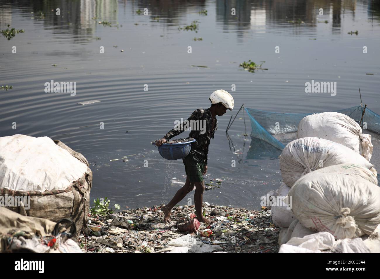 Un travailleur nettoie et collecte les pièces des bouteilles en plastique qui seront recyclées plus tard dans le fleuve Buriganga à Dhaka, au Bangladesh, sur 14 juin 2021. Le fleuve Buriganga, qui coule par la ville de Dhaka, aujourd'hui l'un des fleuves les plus pollués du monde, en raison du déversement endémique des gaspillages humains et industriels. (Photo de Syed Mahamudur Rahman/NurPhoto) Banque D'Images Un travailleur nettoie et collecte les pièces des bouteilles en plastique qui seront recyclées plus tard dans le fleuve Buriganga à Dhaka, au Bangladesh, sur 14 juin 2021. Le fleuve Buriganga, qui coule par la ville de Dhaka, aujourd'hui l'un des fleuves les plus pollués du monde, en raison du déversement endémique des gaspillages humains et industriels. (Photo de Syed Mahamudur Rahman/NurPhoto) Banque D'Images