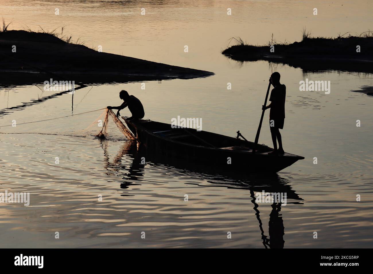 Le pêcheur pond un filet de pêche dans la rivière Brahmaputra au coucher du soleil, à Guwahati, Assam, Inde, le 16 juin 2021. (Photo de David Talukdar/NurPhoto) Banque D'Images