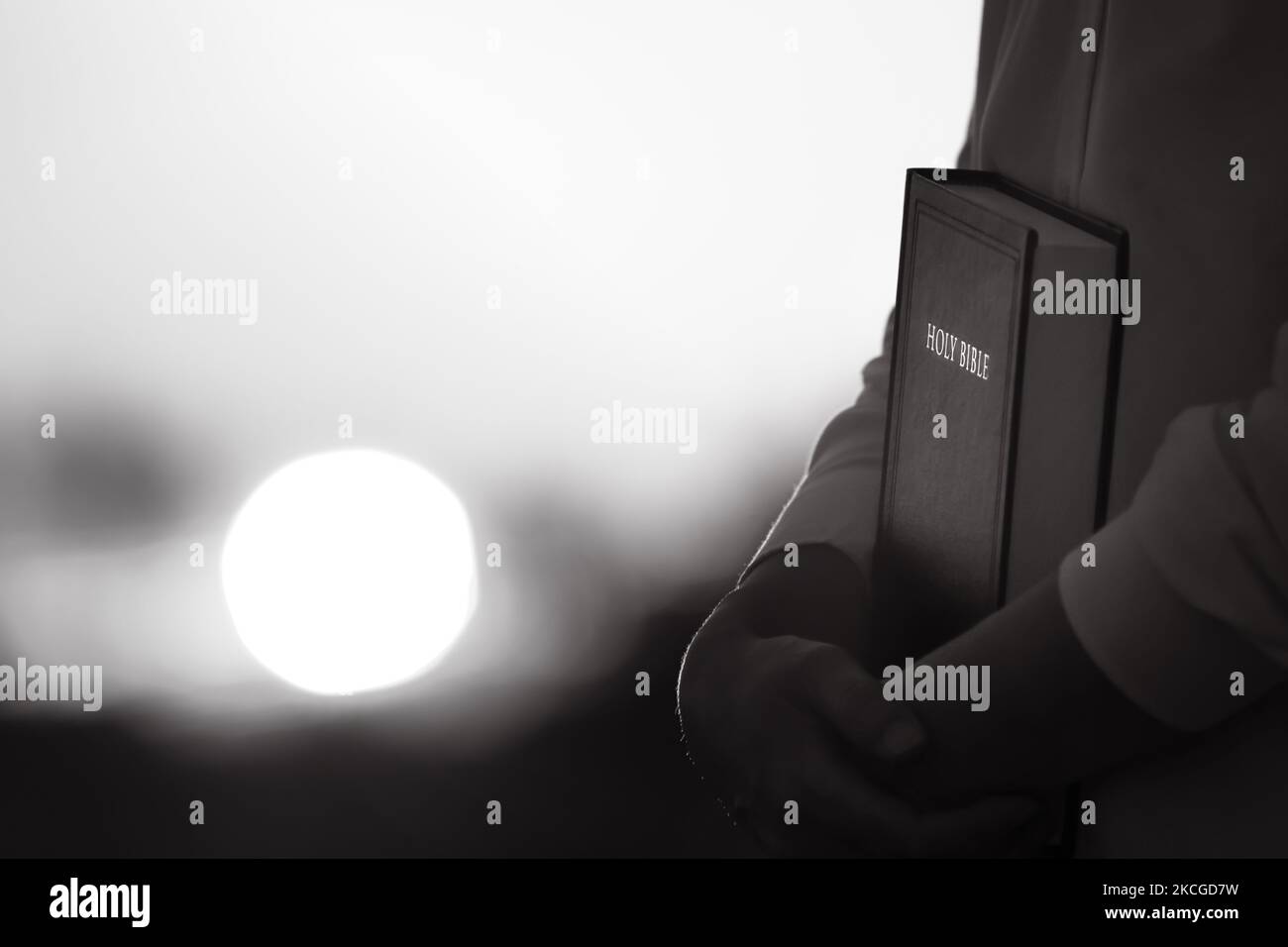 Silhouette chrétienne embrassant et priant avec le paysage de coucher de soleil et la sainte bible Banque D'Images