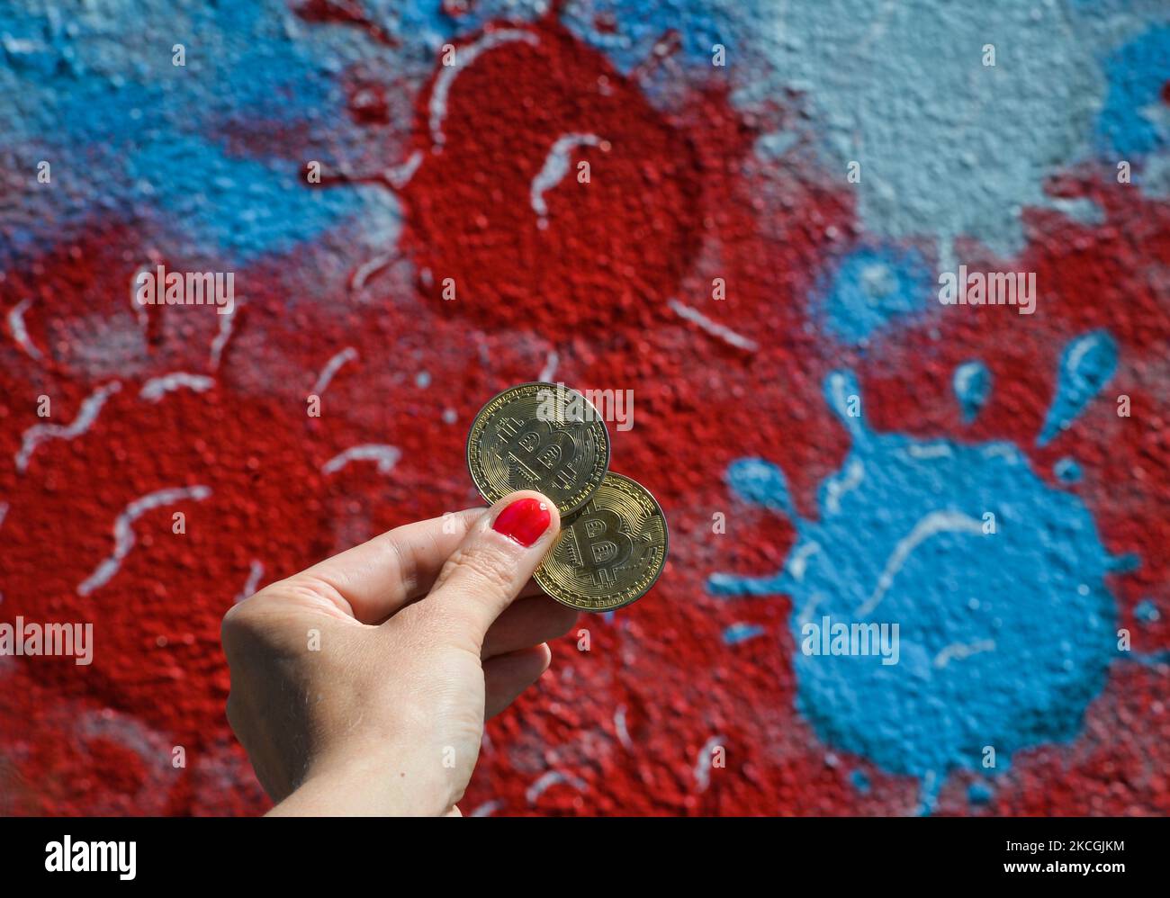 Illustration de deux bitcoins commémoratifs vus devant une murale représentant les molécules du coronavirus. Le dimanche 27 juin 2021, à Dublin, Irlande. (Photo par Artur Widak/NurPhoto) Banque D'Images