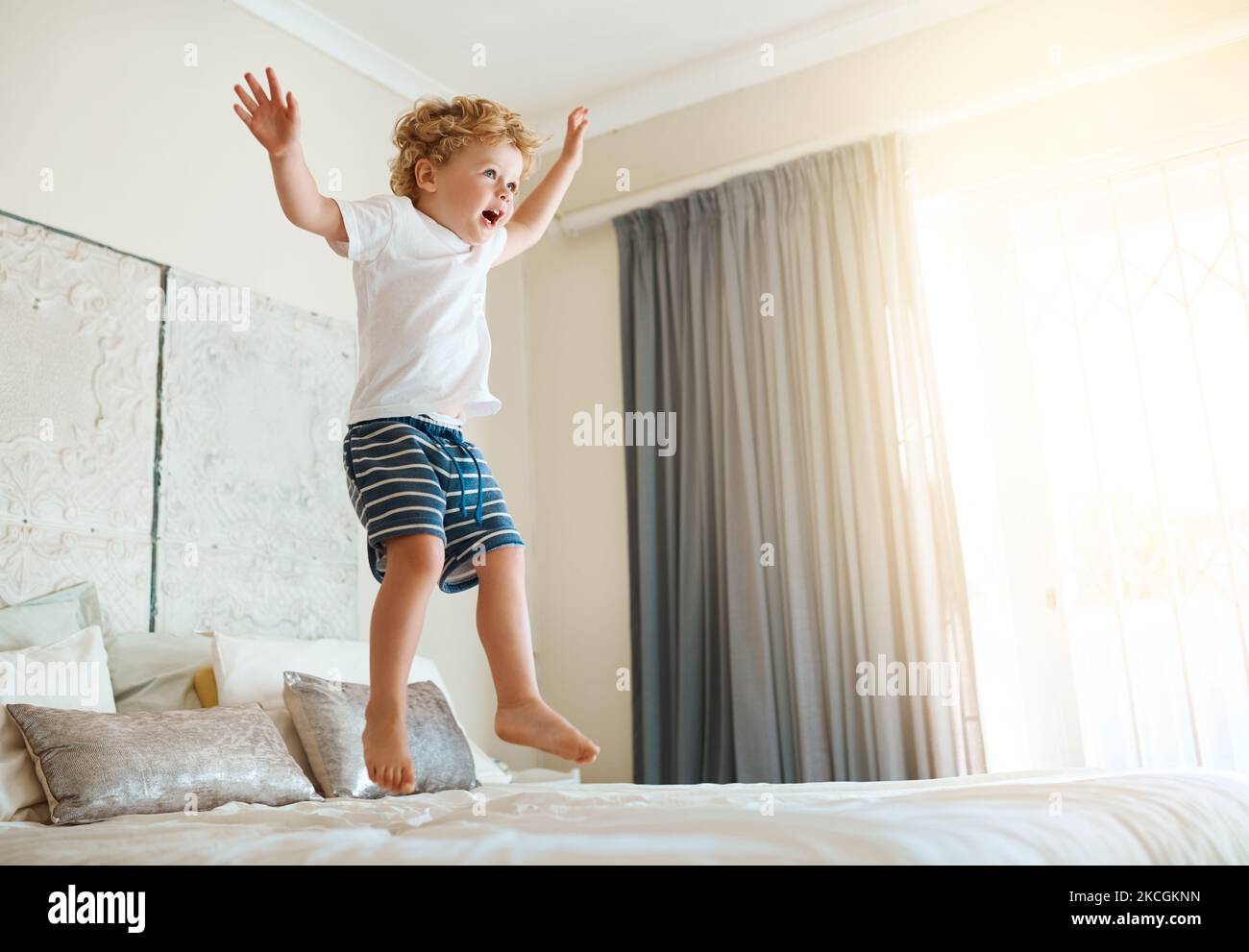 Le lit est mon trampoline. Un adorable petit garçon sautant sur le lit à la  maison Photo Stock - Alamy