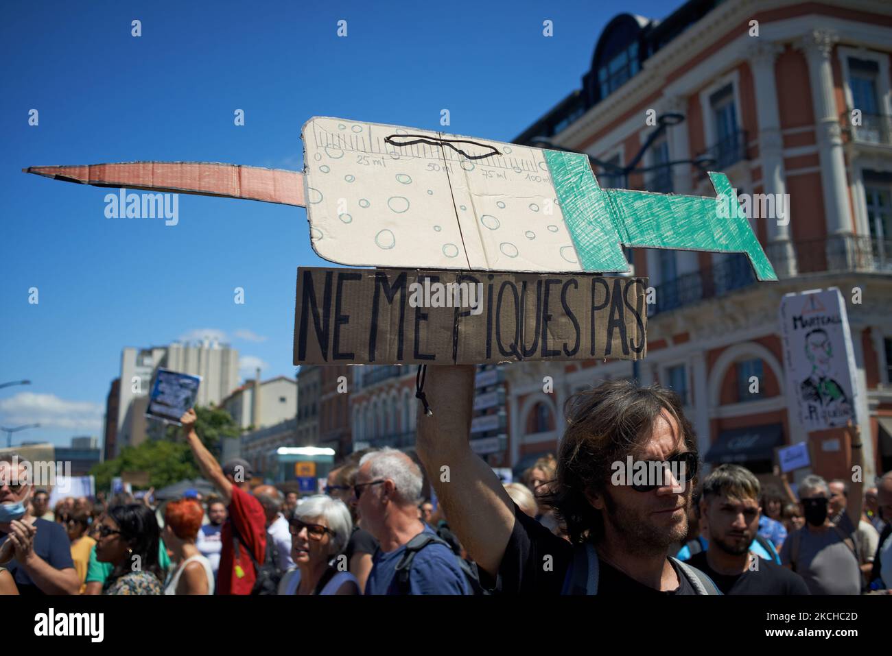 Un manifestant tient une seringue géante qui indique « ne pas me faire jab ». Des milliers de personnes ont protesté à Toulouse et ailleurs en France contre la vaccination presque obligatoire et contre le passe de santé après le discours de Macron sur 12 juillet. Macron a annoncé que la carte sanitaire sera obligatoire pour se rendre dans les lieux publics tels que les cafés, les théats, la salle de concerts, les magasins, les transports en commun (train, Bus, tramway), etc. Le délai entre le premier jab et l'obtention du passe de santé sera de cinq semaines. Mais l'interdiction des espaces publics pour les personnes non vaccinées va s'en prendre à 1 août. Certains disent que c'est comme si Banque D'Images