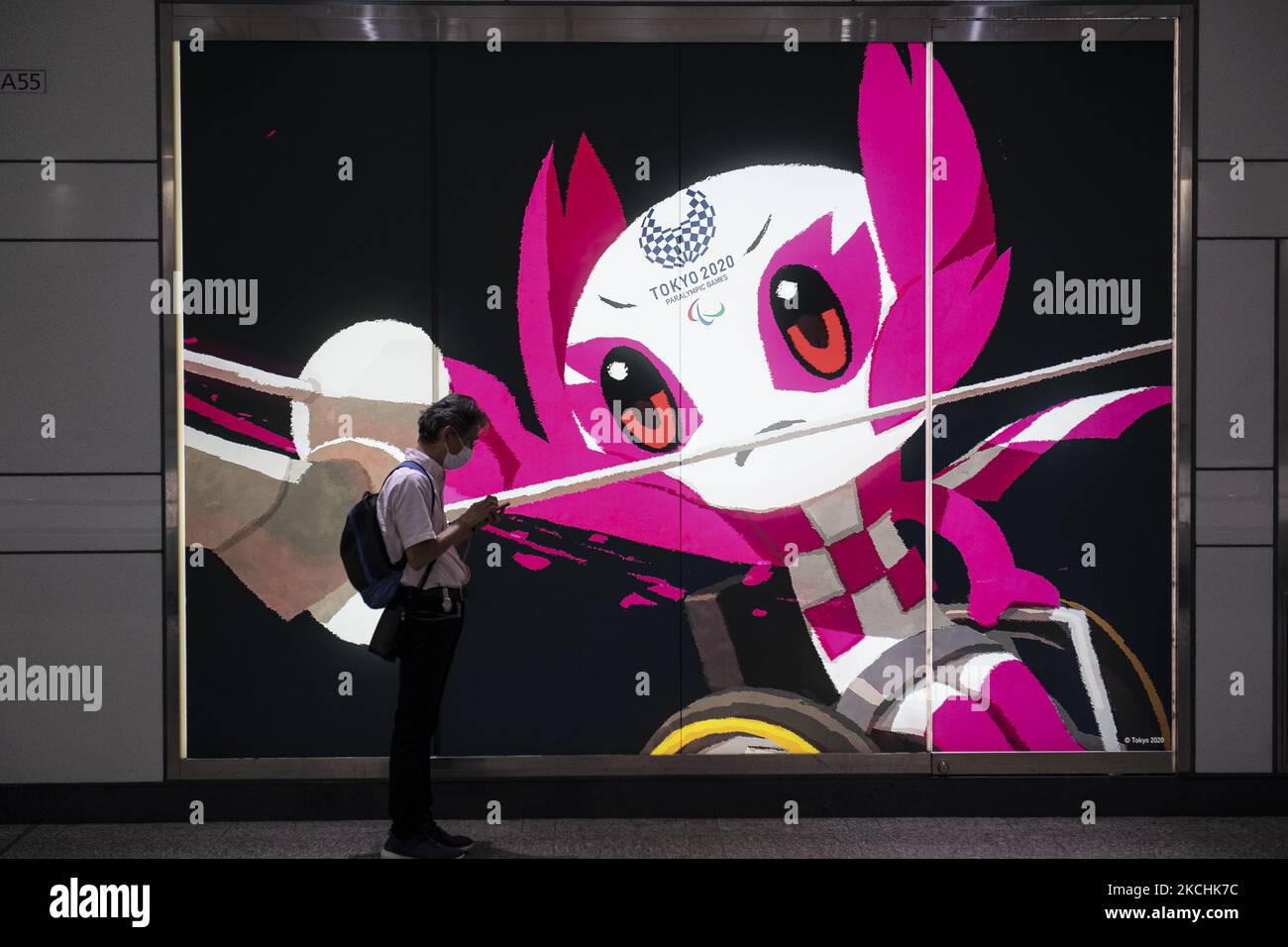 Un homme portant un masque facial de protection joue avec son mobile devant un panneau électronique du personnage des Jeux Olympiques de Tokyo, au Japon, le 23 juillet 2021. (Photo par Yusuke Harada/NurPhoto) Banque D'Images