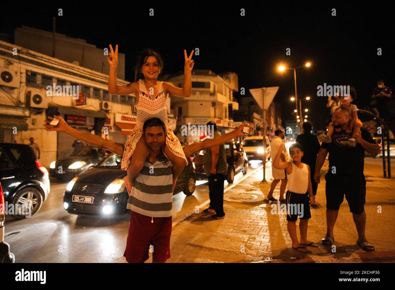Une adolescente est assise sur les épaules de son père alors qu'elle signe la victoire (signe V) alors que les gens sont descendus dans les rues du gouvernorat d'Ariana, près de la capitale Tunis, en Tunisie, sur 25 juillet 2021, pour célébrer la décision du président tunisien Kais de destituer le gouvernement, geler le parlement et suspendre l'immunité de tous les députés. (Photo de Chedly Ben Ibrahim/NurPhoto) Banque D'Images