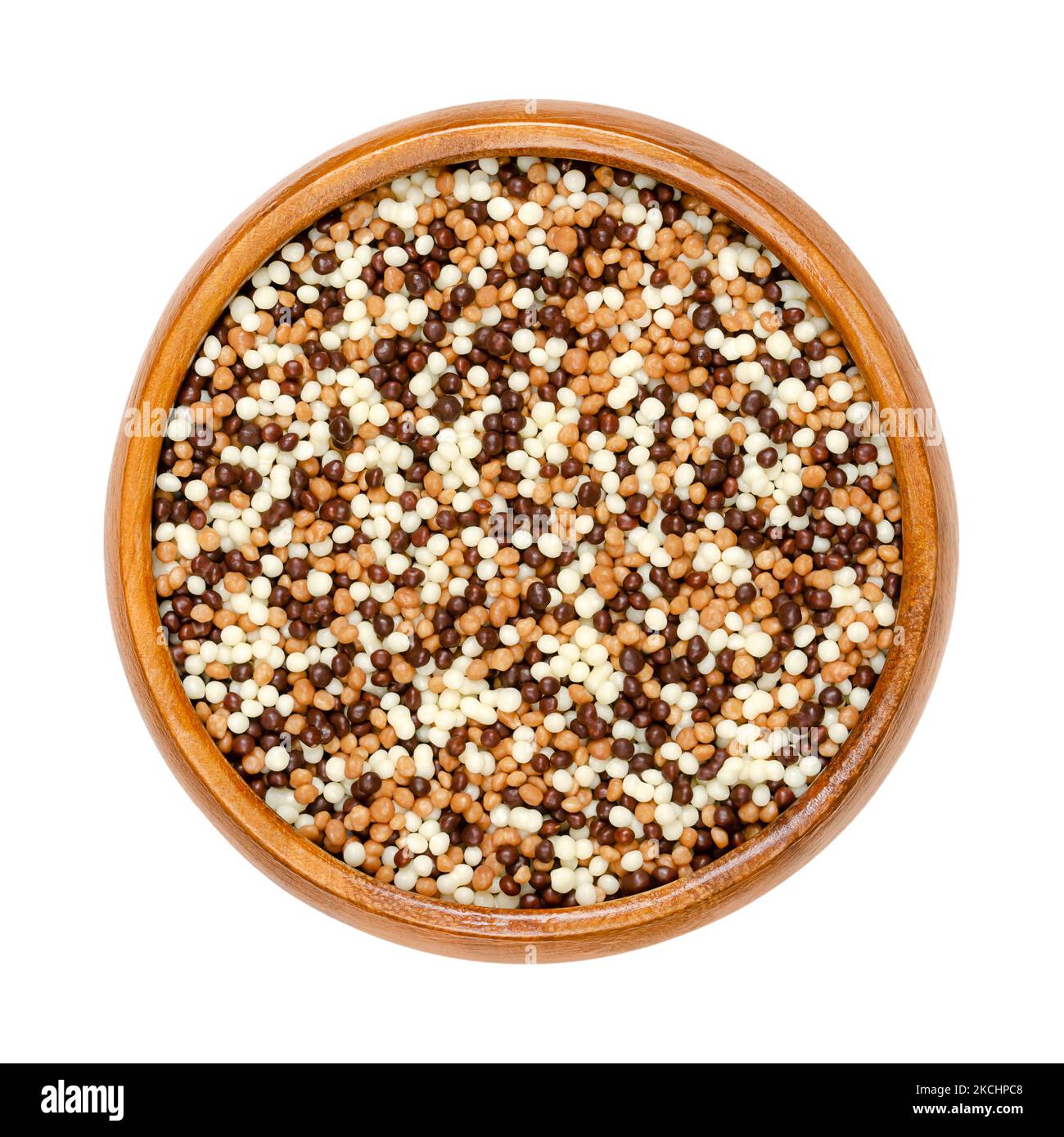 Mini mélange de perles croustillantes au chocolat, dans un bol en bois. Extrusion de céréales croquantes sucrées avec un revêtement de chocolat noir, de lait et blanc. Décoration. Banque D'Images