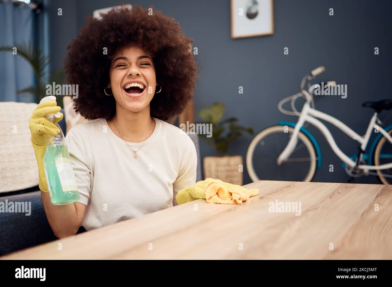 Heureux, nettoyage et pulvérisation avec femme noire et table pour la poussière, les bactéries ou le service d'entretien. Désinfection, hygiène et lavage avec une fille à la maison Banque D'Images