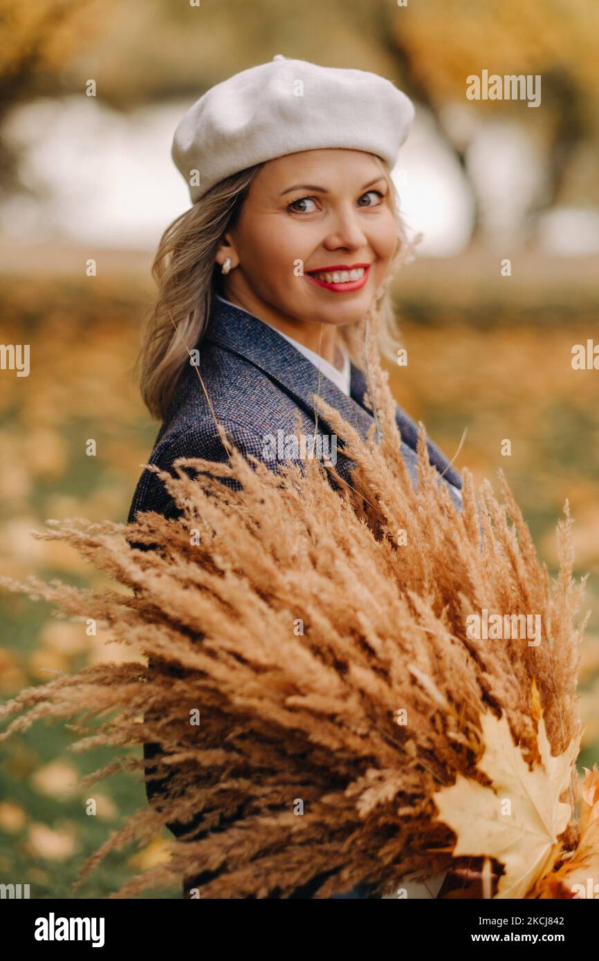 Portrait d'une fille dans une veste et birette avec un bouquet d'automne dans un parc d'automne Banque D'Images