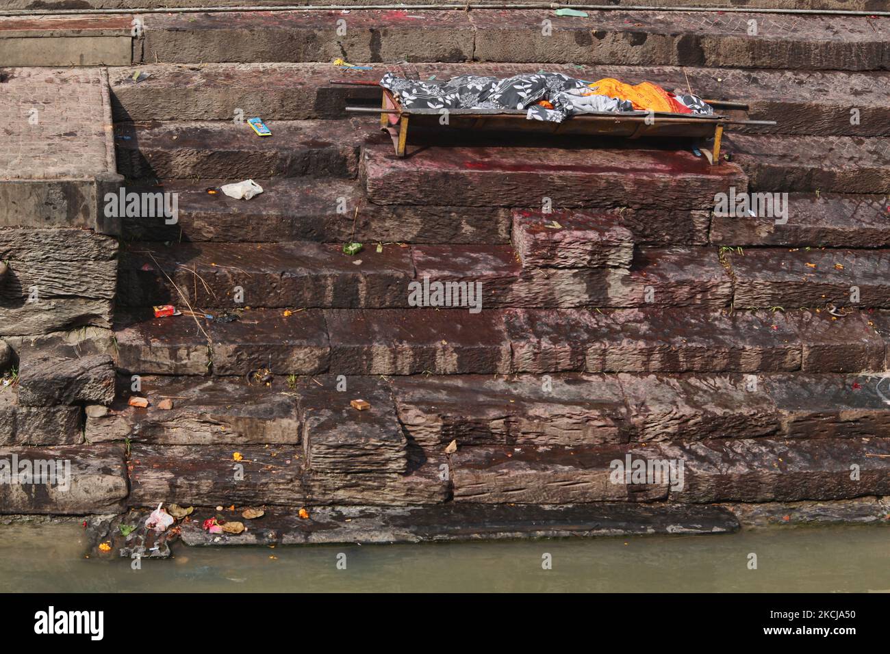 Le corps sur une civière qui attend d'être incinéré repose le long des marches menant à la rive de la rivière Bagmati aux ghats de crémation de Pashupatinath à Katmandou, au Népal, sur 10 décembre 2011. Selon la religion et les traditions hindoues, les morts doivent être incinérés. Les corps sont incinérés selon la coutume et les cendres et les restes sont emportés dans les eaux saintes. Le Bagmati court dans le Gange plus au sud et est considéré comme tout aussi Saint pour les Hindous. Le complexe de Pashupatinath est le plus sacré site hindou du Népal. (Photo de Creative Touch Imaging Ltd./NurPhoto) Banque D'Images
