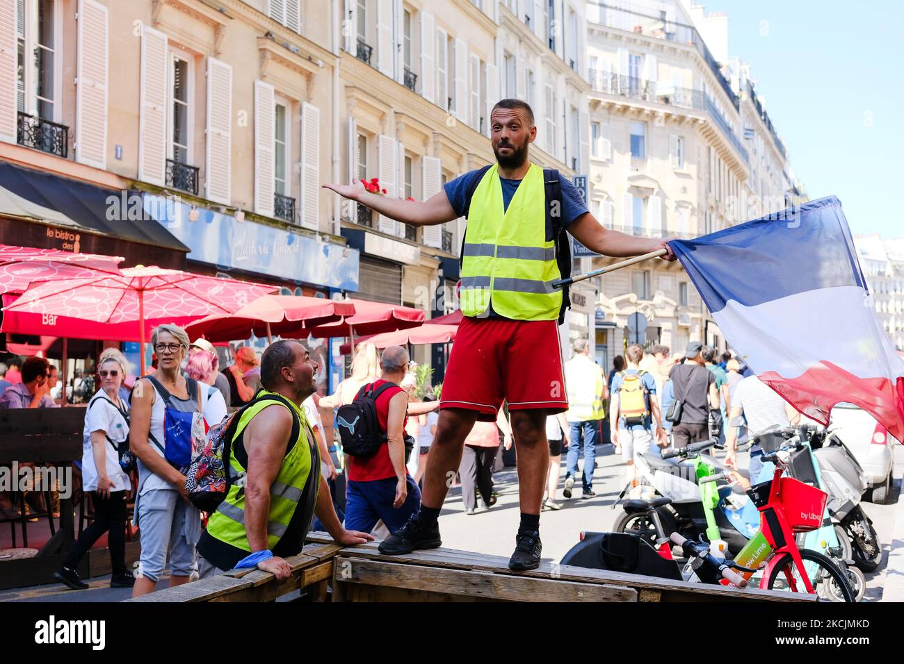 Un gilet jaune fait passer un drapeau français lors de la manifestation contre le passe sanitaire à Paris, en France, sur 14 août 2021. Plus de deux cents événements dans toute la France, alors que depuis lundi, de nouveaux lieux (bars, restaurants, cafés) sont affectés par l'utilisation du passe santé. (Photo de Vincent Koebel/NurPhoto) Banque D'Images
