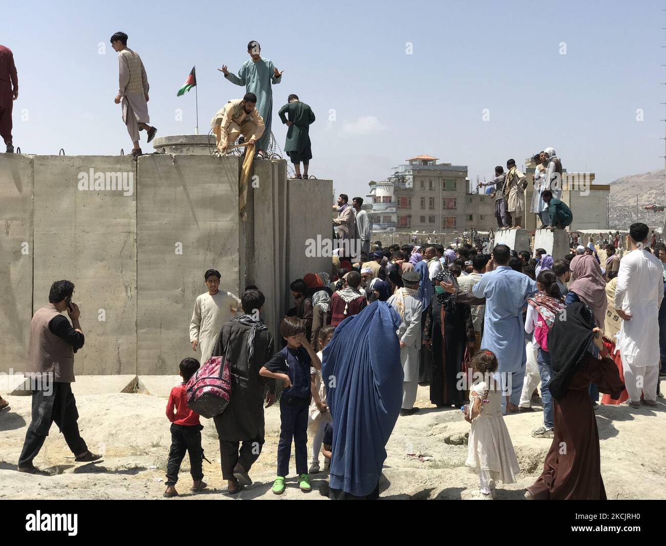 Les gens ont du mal à traverser le mur frontière de l'aéroport international Hamid Karzaï pour fuir le pays après des rumeurs selon lesquelles des pays étrangers évacueraient des personnes même sans visa, après que les talibans aient pris la fuite de Kaboul, en Afghanistan, le 16 août 2021. (Photo par STR/NurPhoto) Banque D'Images