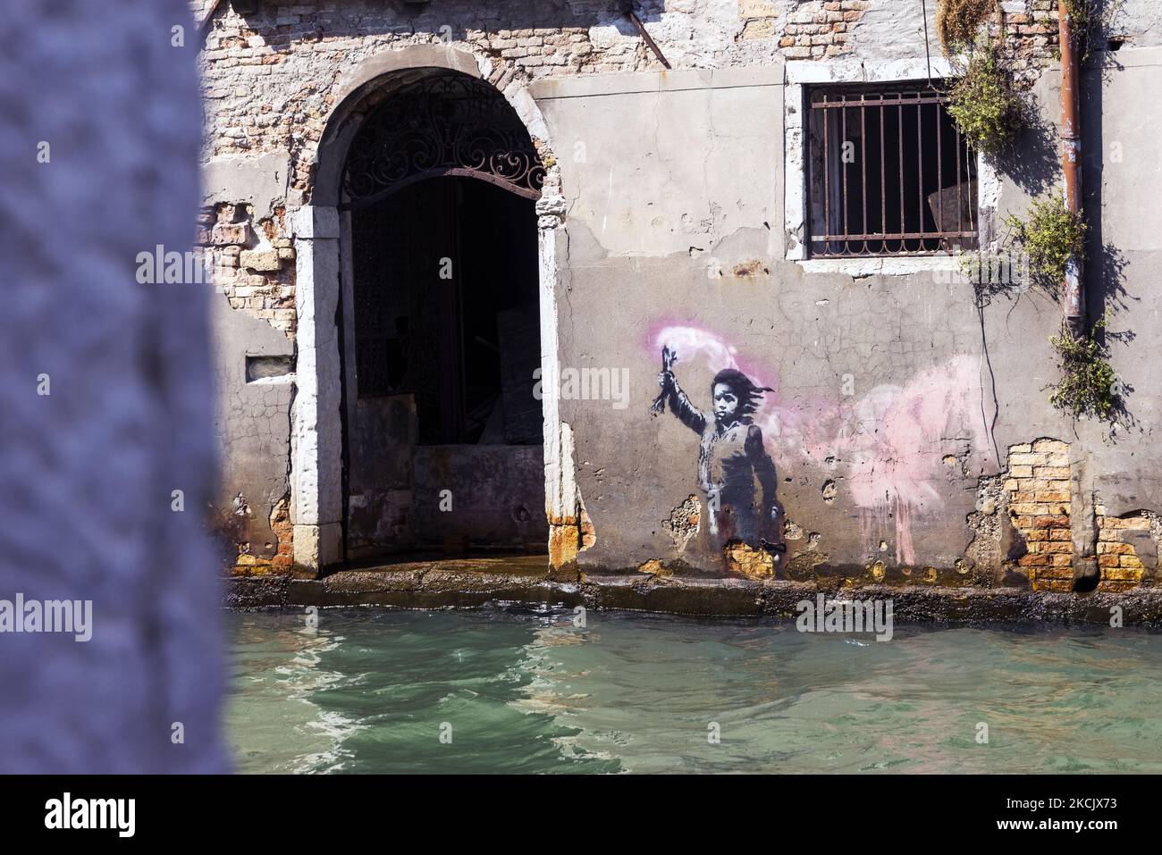 12/08/2021 Venezia, Italie. Une vue sur l'œuvre d'art Banksy présente un enfant migrant portant un gilet de sauvetage et portant une lumière rose fluo. Le graffiti a été peint sur une maison à Rio Novo qui de Piazzale Roma va au Grand Canal à côté de CA' Foscari. Après une année difficile pour le tourisme en raison de la pandémie Covid-19, les touristes, surtout italiens ou européens, reviennent à Venise pour raviver les zones les plus touristiques de la ville. (Photo de Mauro Ujetto/NurPhoto) Banque D'Images