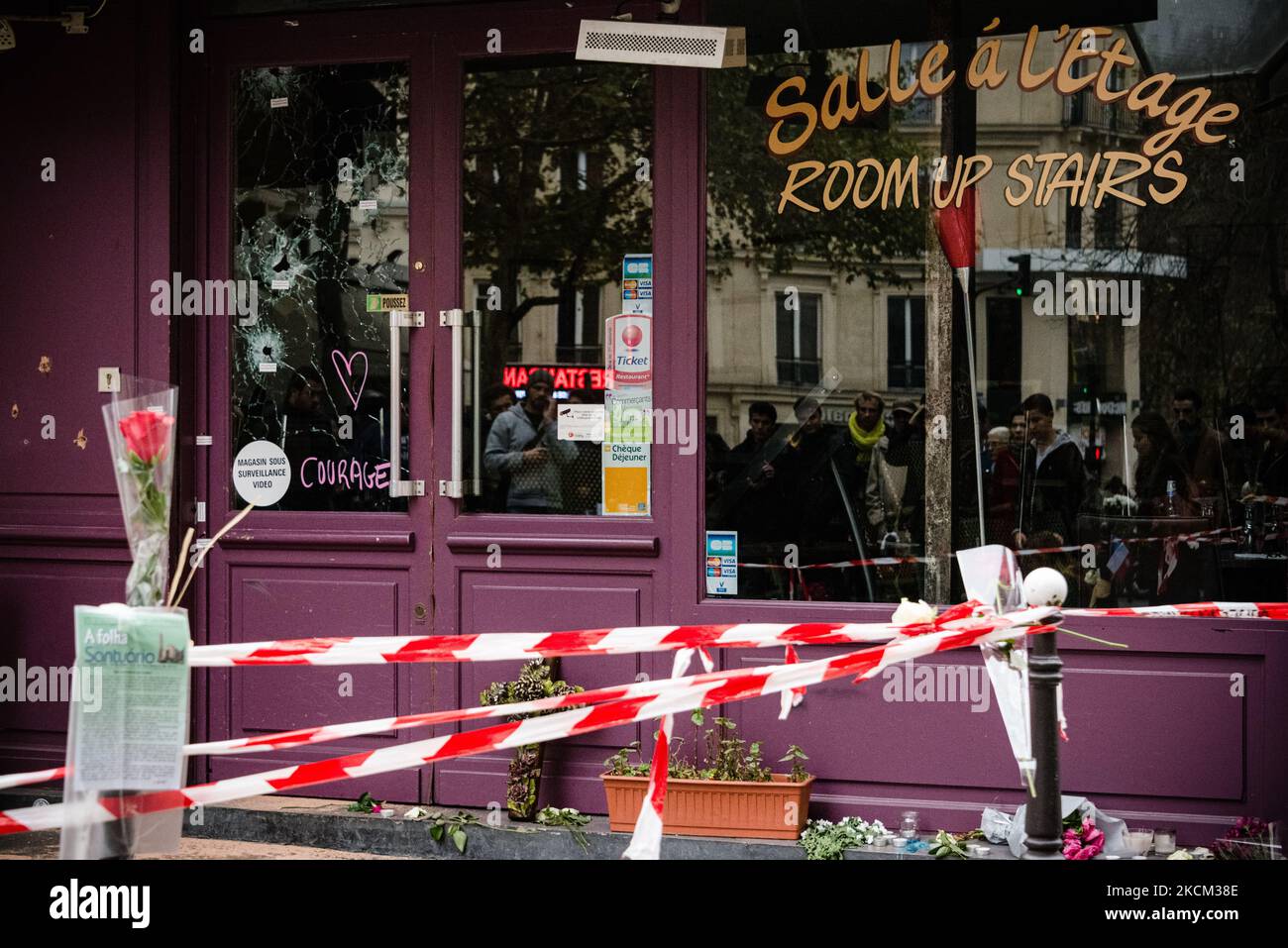 Sur 16 novembre 2015, trois jours après les attaques de 13 novembre 2015 qui ont tué 130 personnes et en ont blessé plus de 400 dans une série d'attaques qui ont frappé plusieurs endroits à Paris, dont le Stade de France, terrasses de café et salle de concert Bataclan l'émotion est à son apogée dans les rues de Paris, comme ici en face de la terrasse du restaurant 'Casa Nostra' où les passants se rassemblent et jettent des fleurs, bougies et messages en hommage aux victimes devant l'un des lieux des attaques encore marqués par l'impact des balles. (Photo de Samuel Boivin/NurPhoto) Banque D'Images