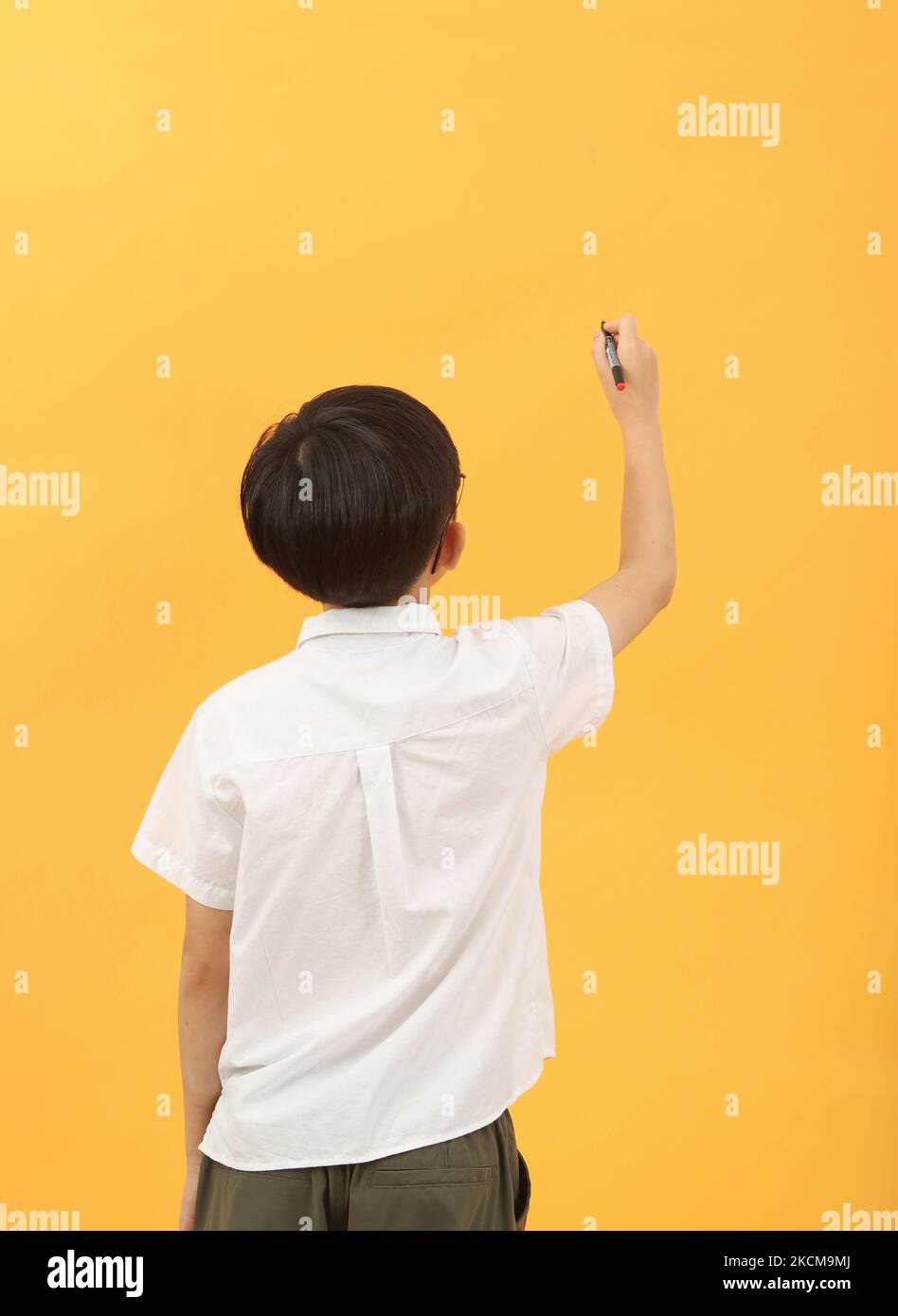 Concept d'éducation avec enfant mâle étudiant tenant la craie et l'écriture sur le tableau noir Banque D'Images