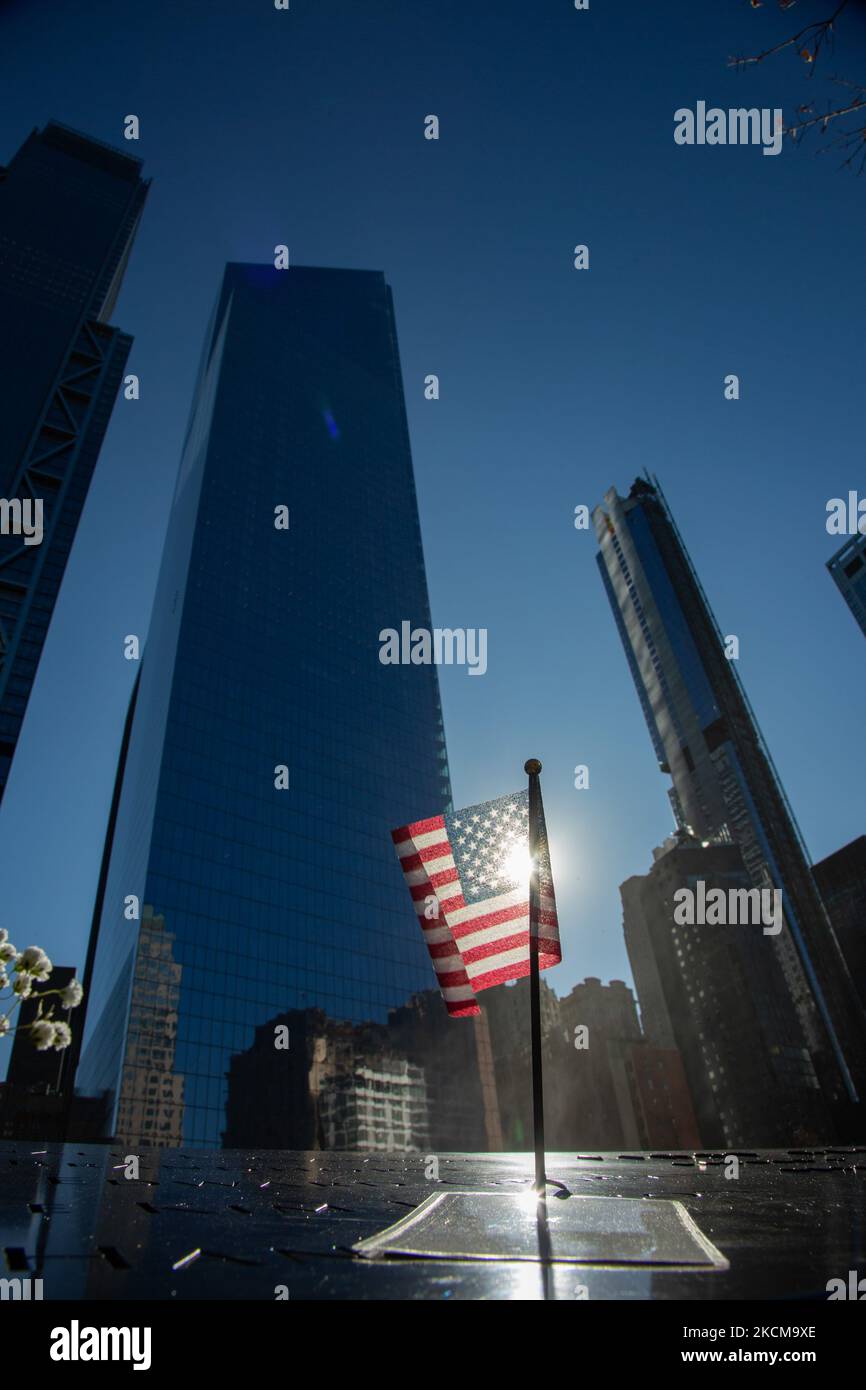 DRAPEAUX AMÉRICAINS sur les noms des victimes contre le soleil avec des fleurs sur le mémorial. Le 20th anniversaire de l'attaque du Centre mondial du commerce qui a eu lieu sur 11 septembre 2001, connu sous le nom de 9/11, est marqué par le retrait complet des forces américaines d'Afghanistan. Site commémoratif du WTC connu sous le nom de Ground Zero ou la pile après les attaques de 11 septembre dans le Lower Manhattan à New York avec deux piscines la piscine nord et la piscine sud à côté du parc commémoratif et du musée avec les noms apparaissant sur les panneaux autour de la piscine. New York City, NY, USA on 25 janvier 2020 (photo de Nicolas Economou/NURP Banque D'Images