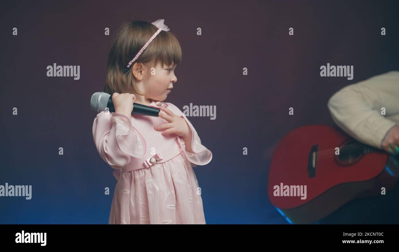 Jolie petite fille dans une robe rose vintage supports avec un microphone sur scène Banque D'Images