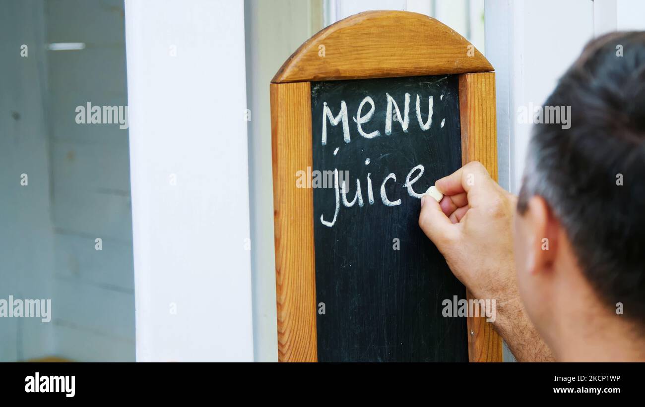 gros plan, sur le tableau noir homme écrivant avec la craie blanche, mots-menu, jus. Photo de haute qualité Banque D'Images