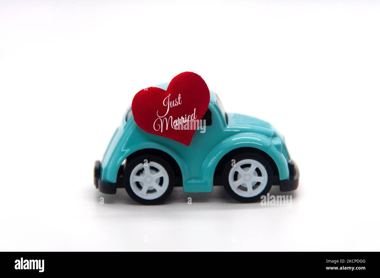 Mini voiture jouet portant la forme de coeur rouge avec texte juste marié. Nouveau concept wed. Banque D'Images