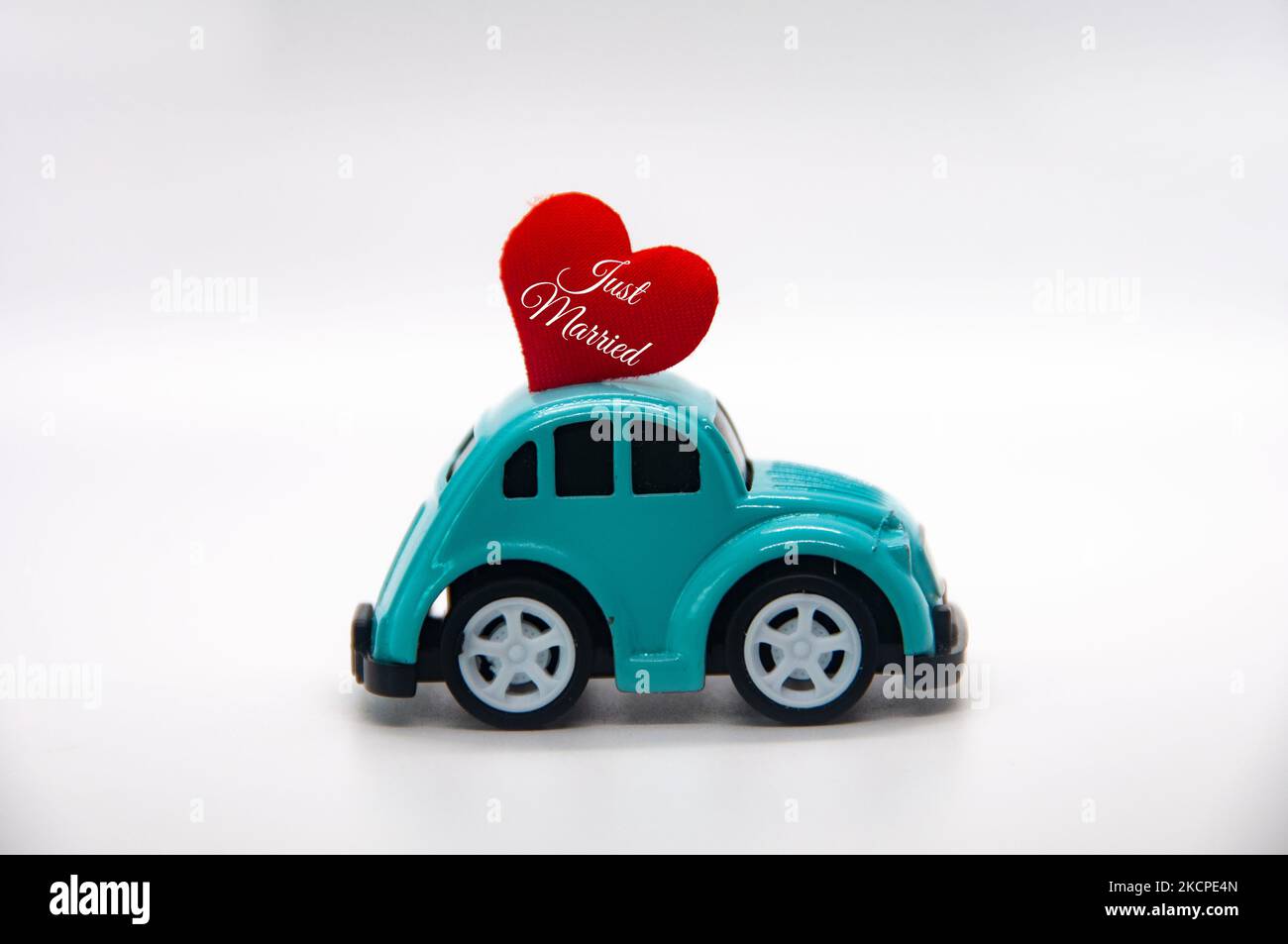 Mini voiture jouet portant la forme de coeur rouge avec texte juste marié. Nouveau concept wed. Banque D'Images