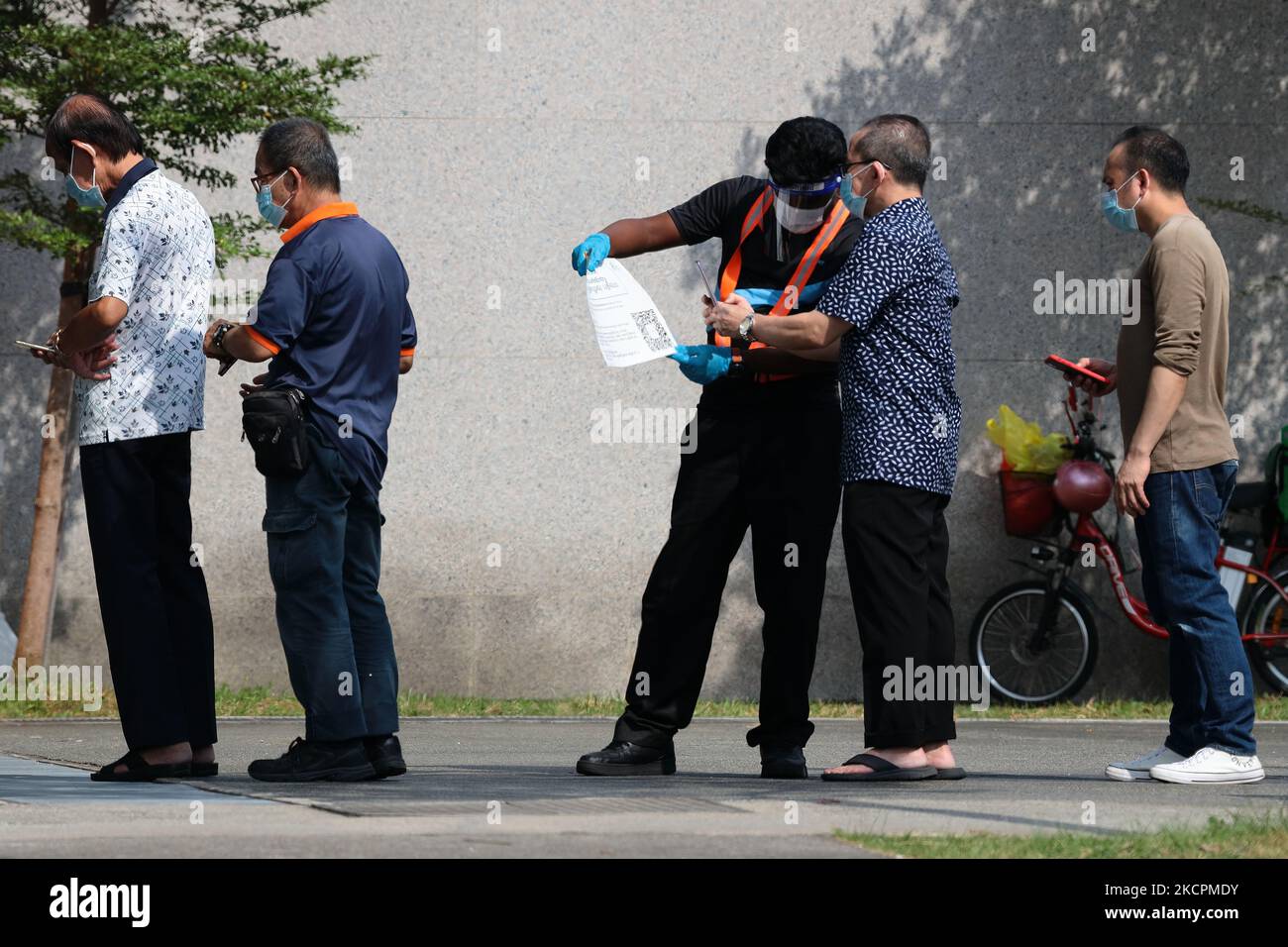 Un officier portant un gant, un masque facial et un masque facial effectue un enregistrement d'entrée en toute sécurité pour les personnes en attente de passer leur test rapide d'antigène COVID-19 à l'extérieur d'un centre de test rapide sur 16 octobre 2021 à Singapour. (Photo de Suhaimi Abdullah/NurPhoto) Banque D'Images