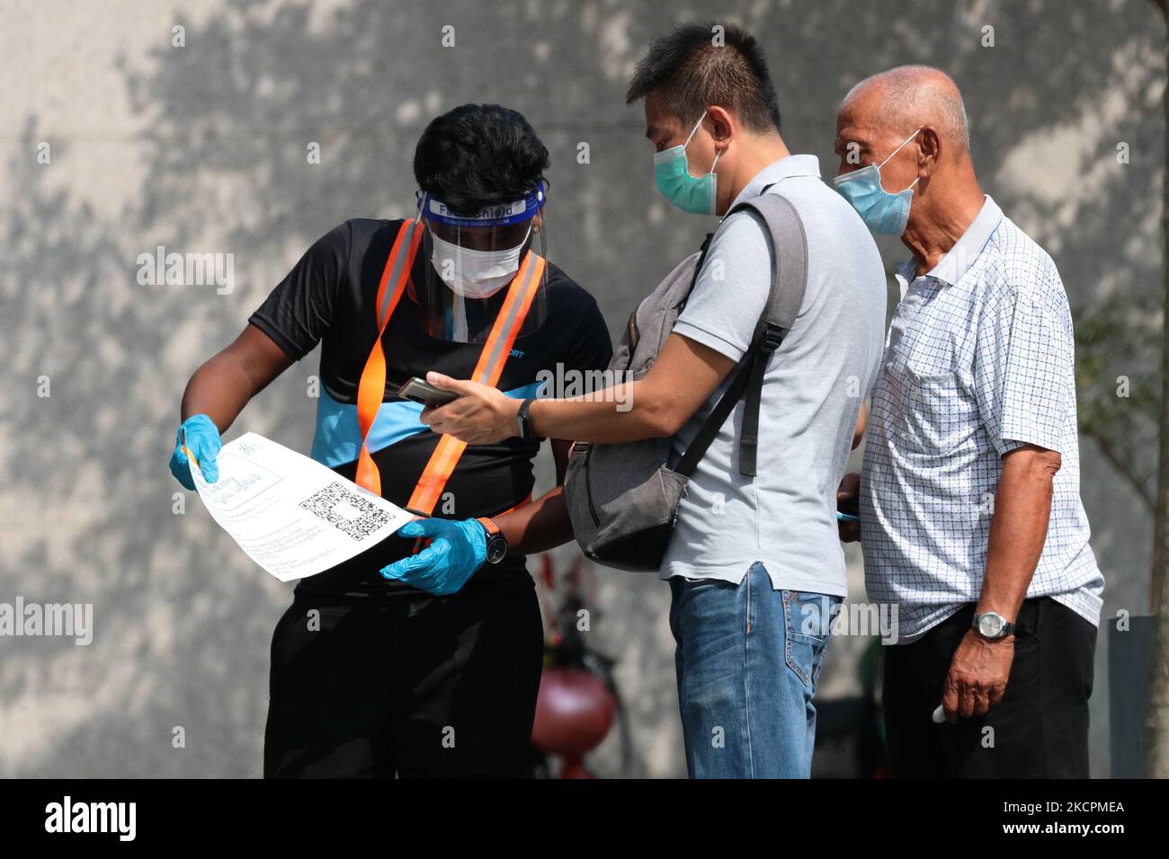Un officier portant un gant, un masque facial et un masque facial effectue un enregistrement d'entrée en toute sécurité pour les personnes en attente de passer leur test rapide d'antigène COVID-19 à l'extérieur d'un centre de test rapide sur 16 octobre 2021 à Singapour. (Photo de Suhaimi Abdullah/NurPhoto) Banque D'Images