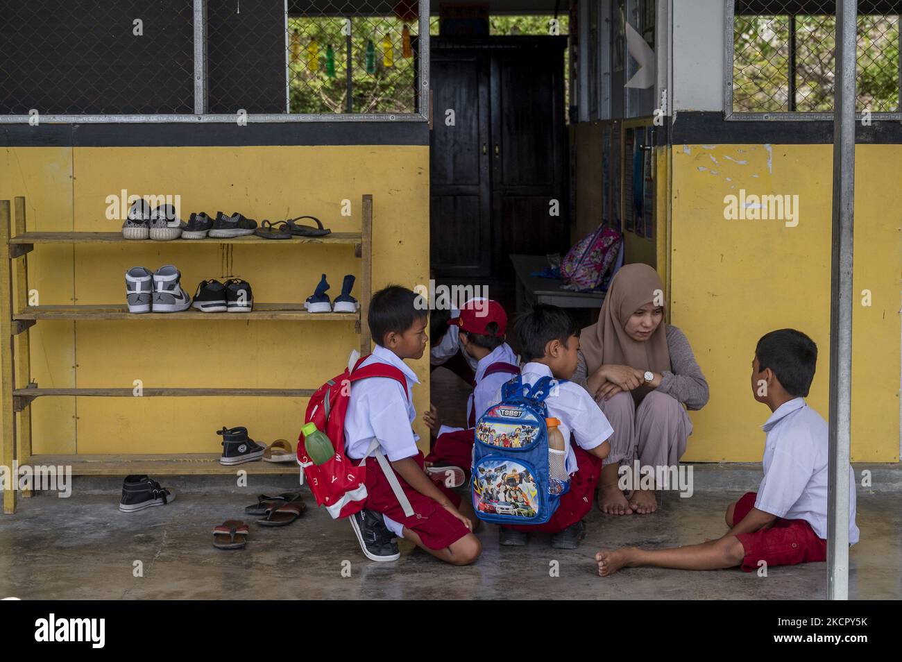 Un enseignant parle avec ses élèves après la première activité d'apprentissage en face à face a eu lieu à l'école d'urgence SD Inpres Balaroa, Palu, province centrale de Sulawesi, Indonésie, sur 18 octobre 2021. Après avoir étudié en ligne en raison de la pandémie COVID-19 pendant près de deux ans, l'école d'urgence située dans le quartier résidentiel de Balaroa continue de mener des activités d'apprentissage direct en mettant en œuvre des protocoles de santé stricts. La décision du gouvernement local de rouvrir les écoles a été prise après que le nombre de cas positifs de COVID-19 dans la région ait connu un déclin significatif. (Photo de Basri Marzu Banque D'Images