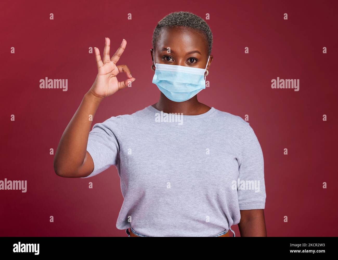Femme noire, covid et ok signe avec masque pour l'approbation, oui et la sécurité avec le geste de la main pour la santé et le bien-être. Portrait du modèle africain pour Banque D'Images