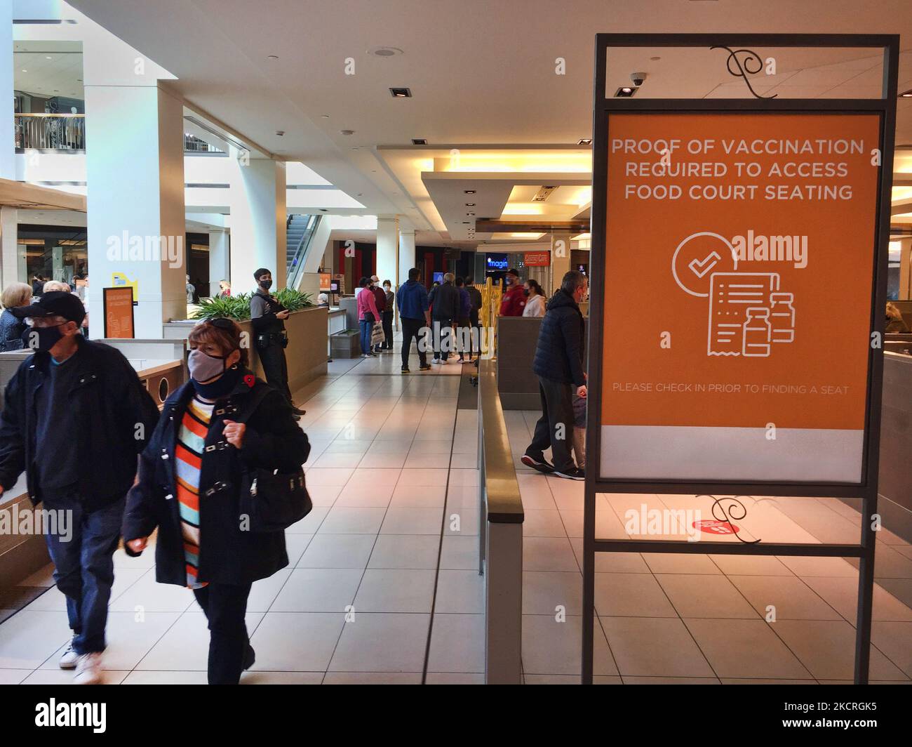 Les gens marchent devant un panneau pour les aviser qu'une preuve de vaccination est requise pour pouvoir dîner dans un centre d'alimentation lors de la pandémie du nouveau coronavirus (COVID-19) à Toronto, Ontario, Canada, on 23 octobre 2021. Tous les résidents de l'Ontario âgés de 12 ans et plus doivent présenter une preuve de vaccination pour dîner dans les restaurants, ainsi que pour visiter des salles de sport, des cinémas et d'autres environnements intérieurs à risque élevé. La province de l'Ontario a annoncé un plan visant à lever toutes les restrictions de santé publique restantes d'ici mars, y compris l'ordonnance sur les masques obligatoires et le système de passeport vaccinal qui n'a fait que s'appliquer Banque D'Images