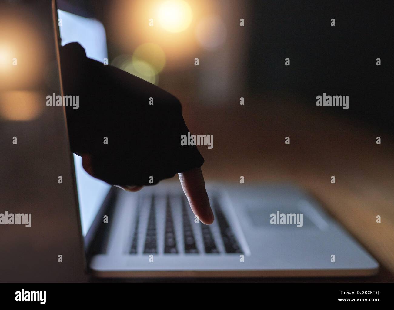 La cybercriminalité est une menace croissante pour tous. Un hackers a désincarné la main qui atteint à travers un écran d'ordinateur portable. Banque D'Images