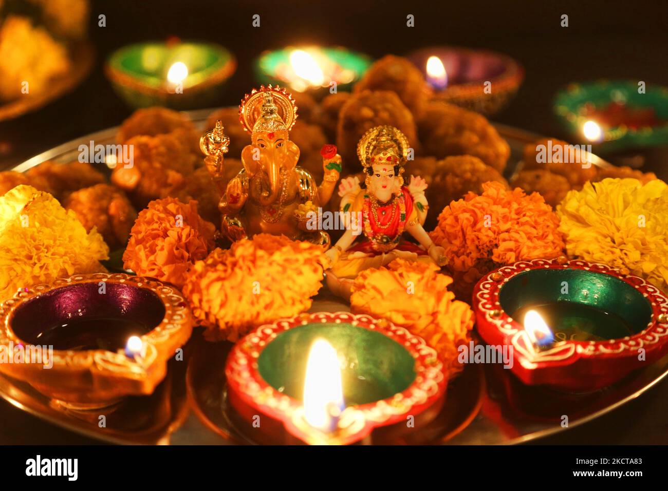 Diyas (petites lampes en argile) entoure les idoles de la Déesse Lakshmi (Déesse Laxmi) et de Lord Ganesh sur un plateau de ladoos (bonbons indiens) pendant le festival de Diwali à un temple hindou à Toronto, Ontario, Canada, on 04 novembre 2021. (Photo de Creative Touch Imaging Ltd./NurPhoto) Banque D'Images