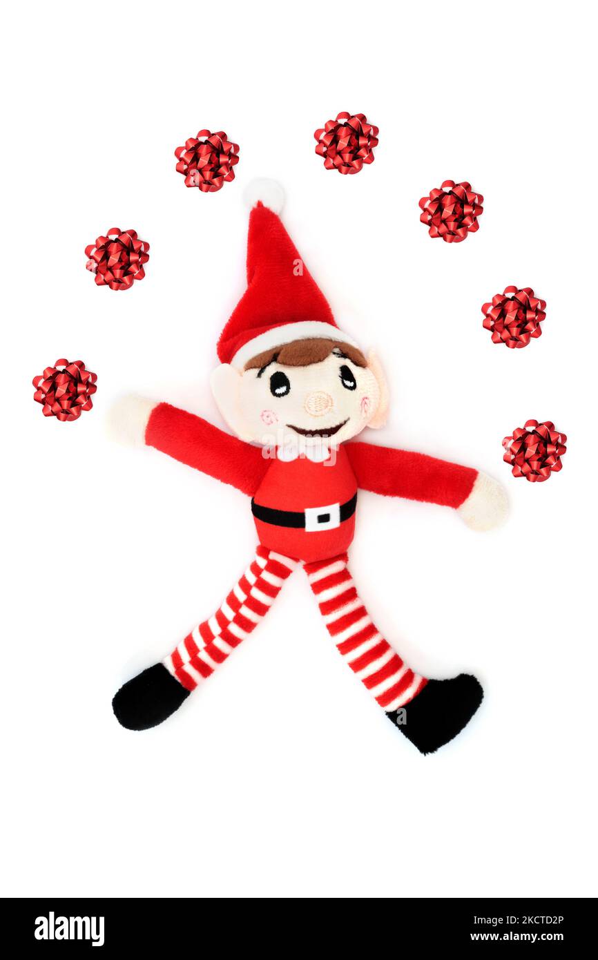 Orf de Noël jonglant rouge noeuds décorations rétro santa aide jouet festif sur fond blanc. Composition amusante pour les fêtes de fin d'année. Banque D'Images