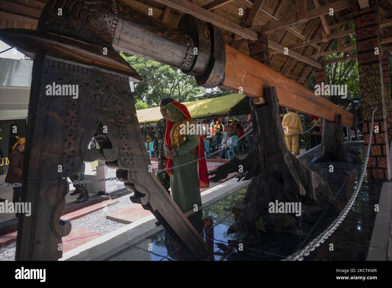 Les résidents marchent près d'un géant de 7,7 mètres et 1,2 tonnes d'arme traditionnelle GUMA placé en face d'un musée à Palu, province centrale de Sulawesi, Indonésie sur 10 novembre 2021. L'arme traditionnelle de la tribu Kaili - le groupe ethnique majoritaire qui habite la vallée de Palu, a été sculptée pour être exposée au public avant d'être déposée dans un musée. La construction du GUMA géant a été initiée par le commandant du brigadier général Farid Makruf du 132/Tadulako Military Resort après avoir mené une recherche sur l'histoire de la résistance des populations locales à l'occupation étrangère. En fait, le GUMA original nous Banque D'Images