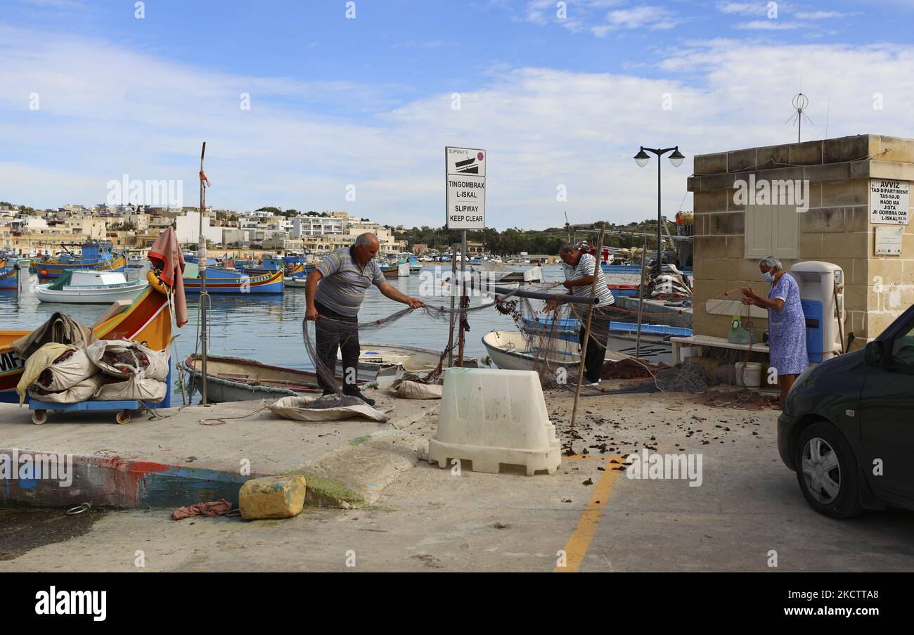 Une famille de pêcheurs démêle ses filets de pêche après une excursion de pêche matinale dans le village de pêcheurs de Marsaxlokk, au sud-est de Malte. Malte, samedi, 13 novembre 2021. (Photo de Danil Shamkin/NurPhoto) Banque D'Images