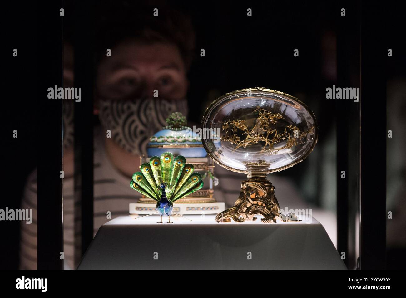 LONDRES, ROYAUME-UNI - 17 NOVEMBRE 2021 : un membre du personnel regarde l'œuf de Peacock (R) et le berceau avec l'œuf de Garlands lors d'une séance photo pour la prochaine exposition 'Faberge à Londres: Romance to Revolution' au V&A (20 novembre 2021 – 8 mai 2022), le 17 novembre 2021 à Londres, en Angleterre. La grande exposition du V&A avec plus de 200 objets exposés, dont une collection d’œufs de Pâques impériaux, explorera le savoir-faire du maître-d’œuvre russe Carl Faberge et la nature anglo-russe de son entreprise. (Photo de Wiktor Szymanowicz/NurPhoto) Banque D'Images