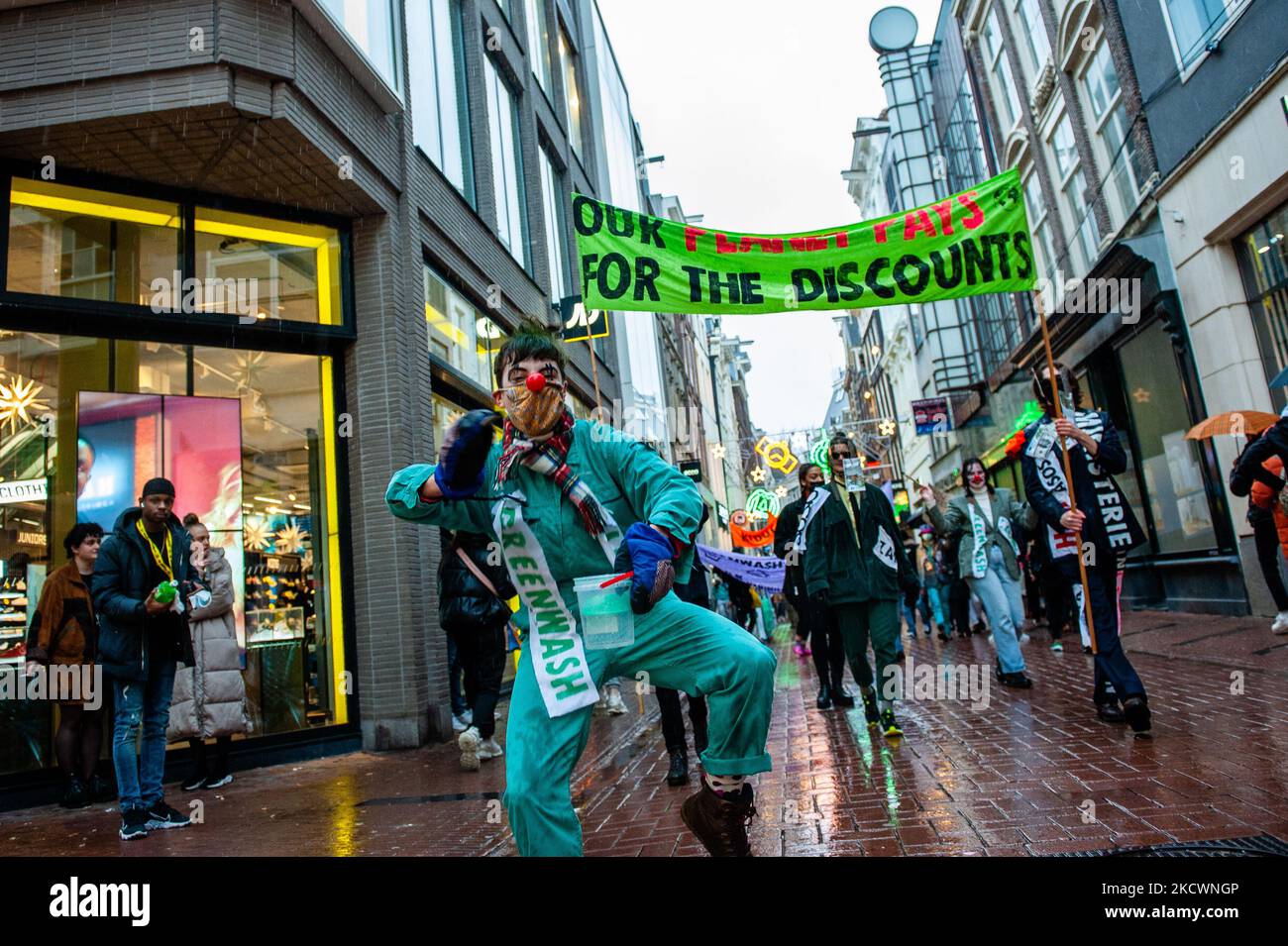 Un clown représentant les pratiques de lavage vert réalisées par les marques de mode, fait semblant de peindre avec de la peinture verte, lors d'un défilé de mode rapide moqueuse organisé par XR, contre le Black Friday à Amsterdam, sur 27 novembre 2021. (Photo par Romy Arroyo Fernandez/NurPhoto) Banque D'Images