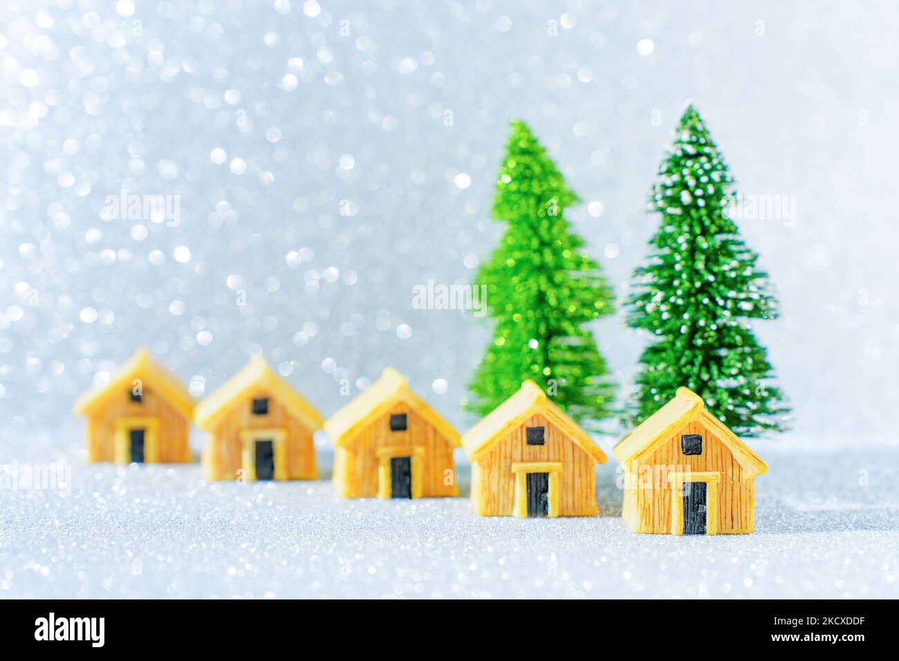 Ensemble de chalets en bois similaires placés par deux arbres de Noël en peluche sur fond étincelant. Concept de circuit des vacances d'hiver. Banque D'Images