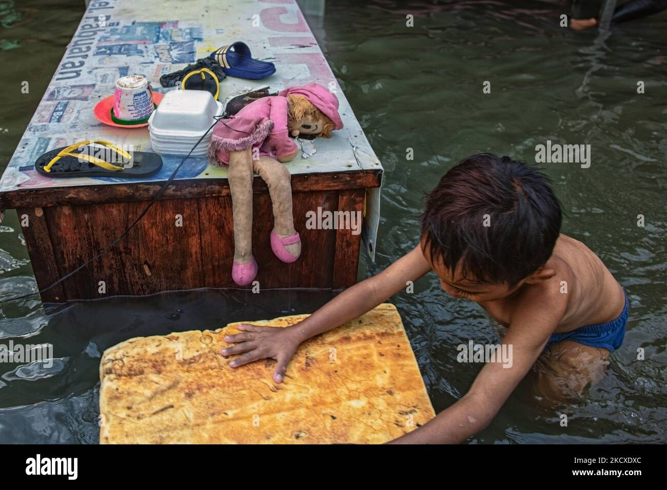 Un petit garçon jouant sur l'eau lors d'une marée dans la zone côtière de Jakarta, Muara Angke, le 7 décembre 2021. Les autorités locales ont prédit que des marées et des vents violents frapperont la région de la baie de Jakarta et le nord de W. Java du 6 au 9 décembre, ce qui provoquerait l'immersion de la zone côtière de la capitale et endommagera les maisons. Les inondations causées par le débordement d'eau de mer ont submergé 15 unités de quartier dans le nord de Jakarta et l'ouest de Jakarta. (Photo par Afriadi Hikmal/NurPhoto) Banque D'Images