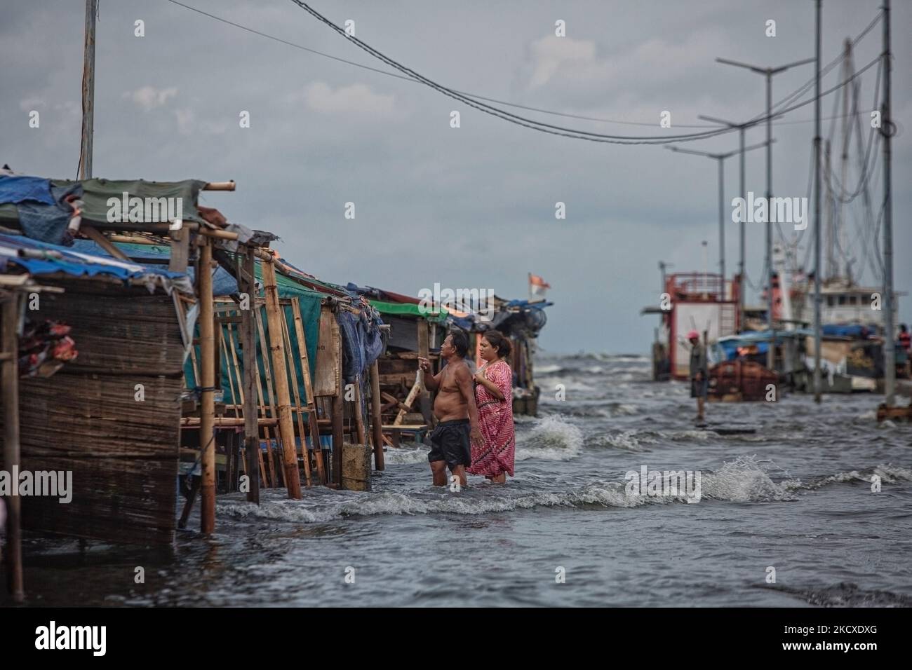 Les résidents passent par une cabine de nourriture endommagée par les vagues de marée dans la zone côtière de Jakarta, Muara Angke, le 7 décembre 2021. Les autorités locales ont prédit que des marées et des vents violents frapperont la région de la baie de Jakarta et le nord de W. Java du 6 au 9 décembre, ce qui provoquerait l'immersion de la zone côtière de la capitale et endommagera les maisons. Les inondations causées par le débordement d'eau de mer ont submergé 15 unités de quartier dans le nord de Jakarta et l'ouest de Jakarta. (Photo par Afriadi Hikmal/NurPhoto) Banque D'Images