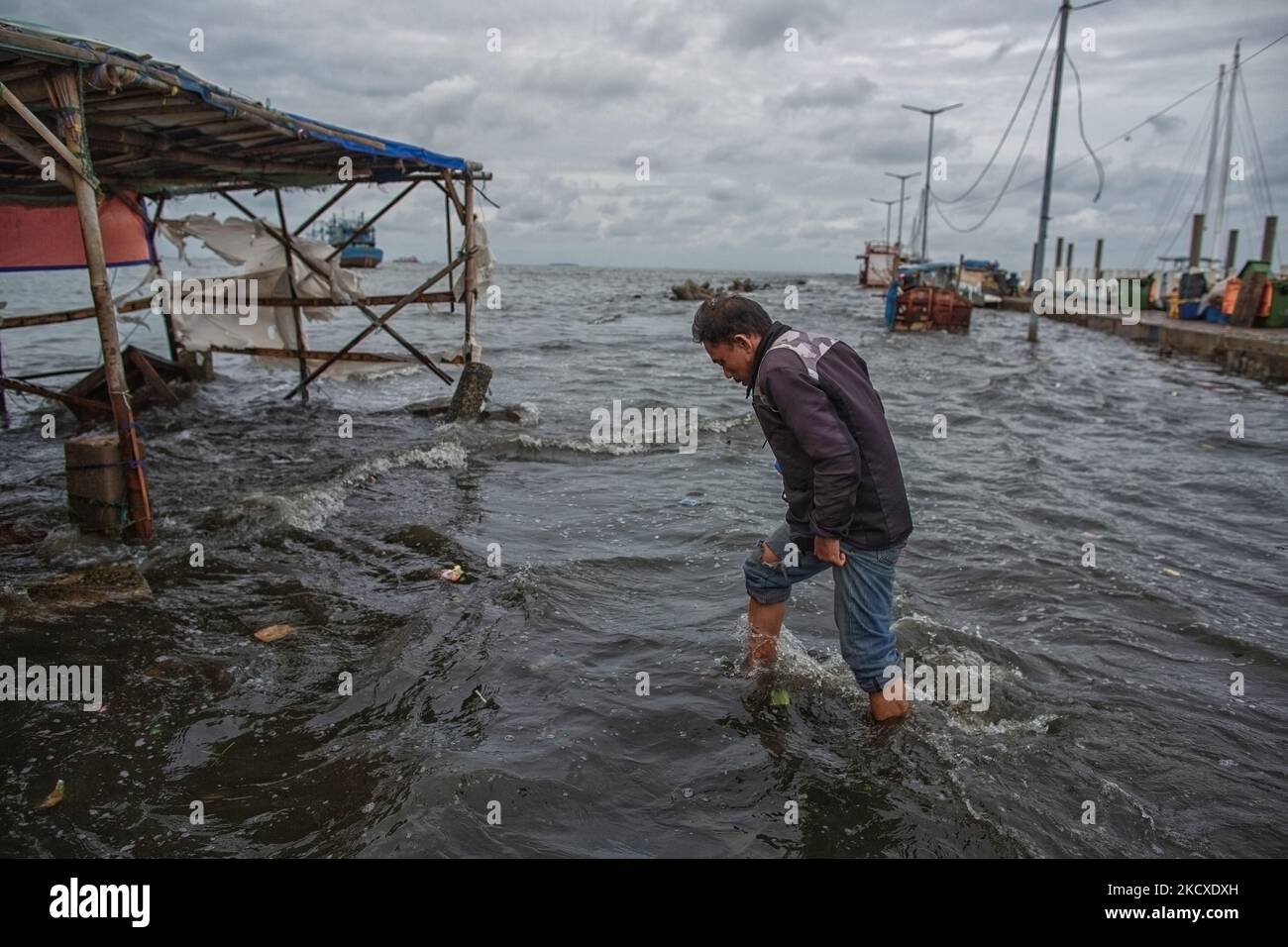 Le 7 décembre 2021, un homme passe devant une cabine de nourriture endommagée par les vagues de marée dans la zone côtière de Jakarta, Muara Angke. Les autorités locales ont prédit que des marées et des vents violents frapperont la région de la baie de Jakarta et le nord de W. Java du 6 au 9 décembre, ce qui provoquerait l'immersion de la zone côtière de la capitale et endommagera les maisons. Les inondations causées par le débordement d'eau de mer ont submergé 15 unités de quartier dans le nord de Jakarta et l'ouest de Jakarta. (Photo par Afriadi Hikmal/NurPhoto) Banque D'Images