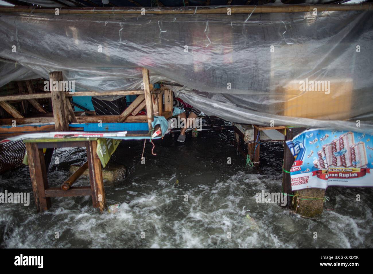 Une femme qui sied dans une cabine de nourriture pendant les vagues de marée dans la zone côtière de Jakarta, Muara Angke, le 7 décembre 2021. Les autorités locales ont prédit que des marées et des vents violents frapperont la région de la baie de Jakarta et le nord de W. Java du 6 au 9 décembre, ce qui provoquerait l'immersion de la zone côtière de la capitale et endommagera les maisons. Les inondations causées par le débordement d'eau de mer ont submergé 15 unités de quartier dans le nord de Jakarta et l'ouest de Jakarta. (Photo par Afriadi Hikmal/NurPhoto) Banque D'Images